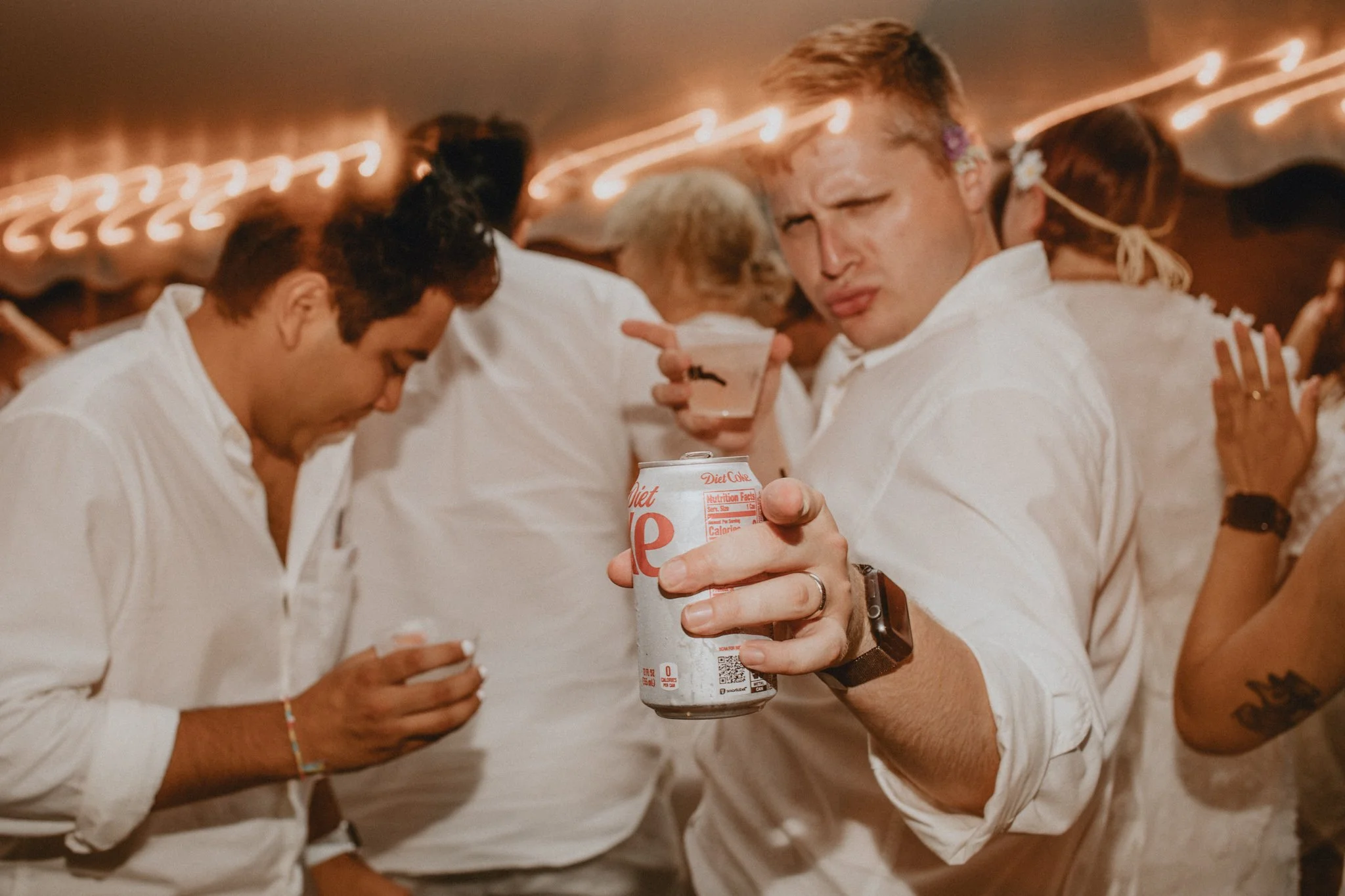 wedding guests, in all white, dance and point towards the camera