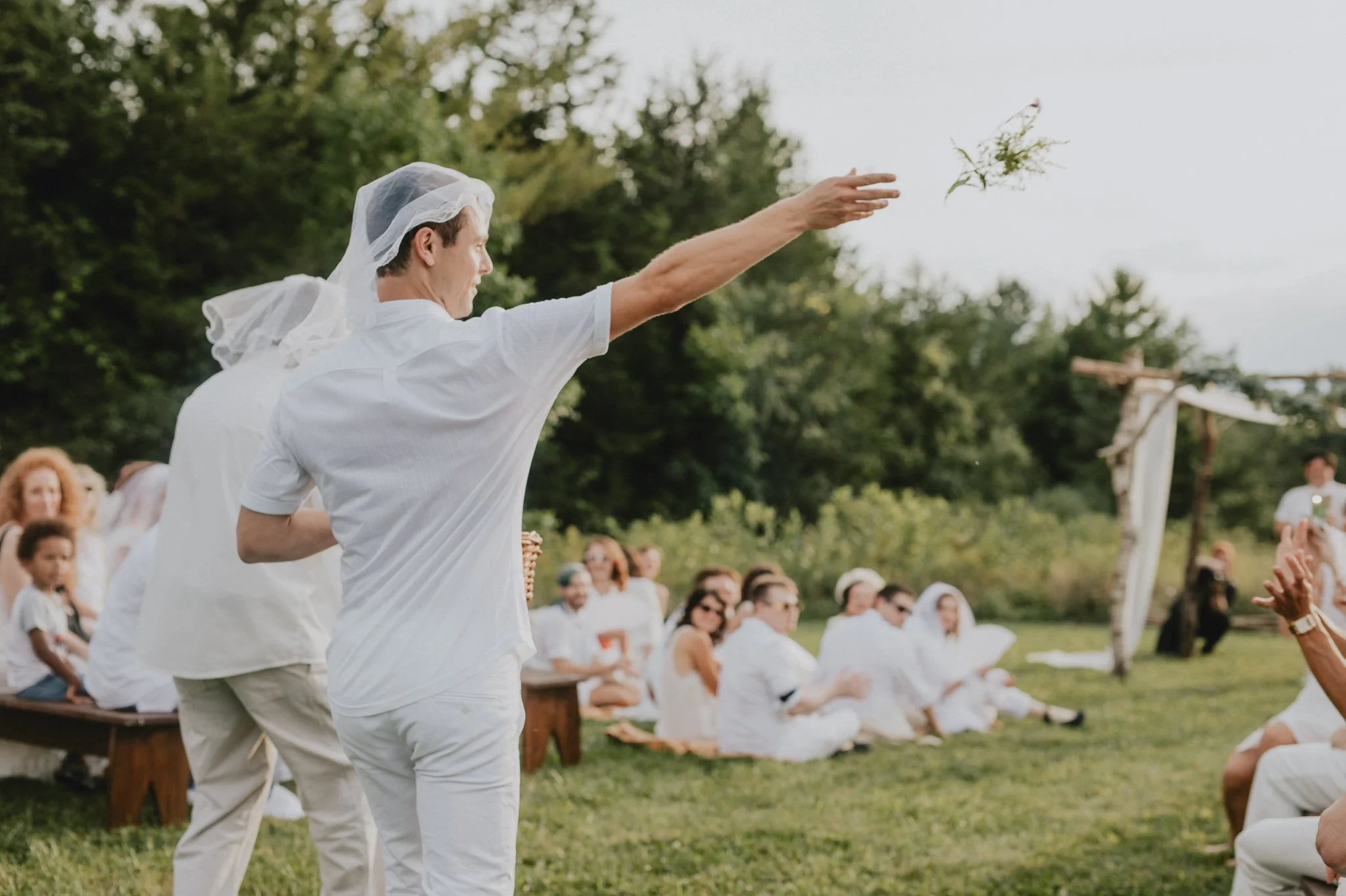 The brothers of the brides, two grown men, toss flowers as they walk down the aisle