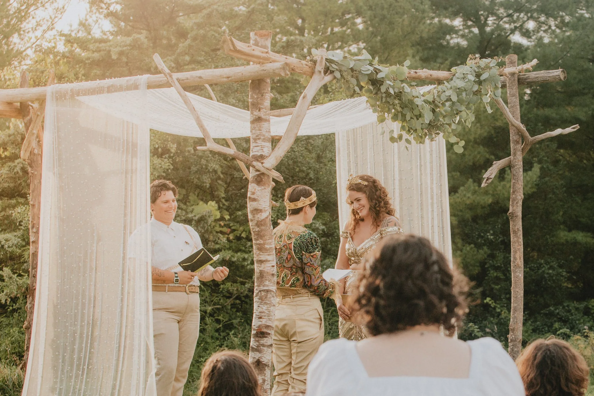 The brides share vows under their chuppa as the sun sets behind them