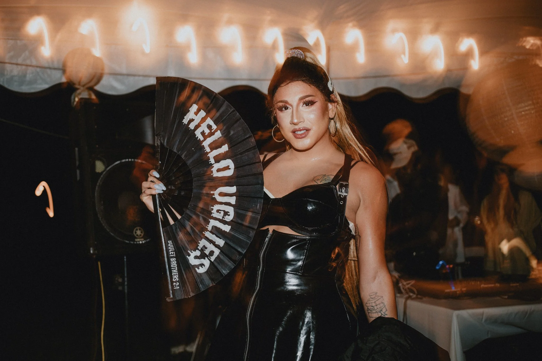 Ariana Grande impersonator in all black, with a fan that reads Hello Uglies