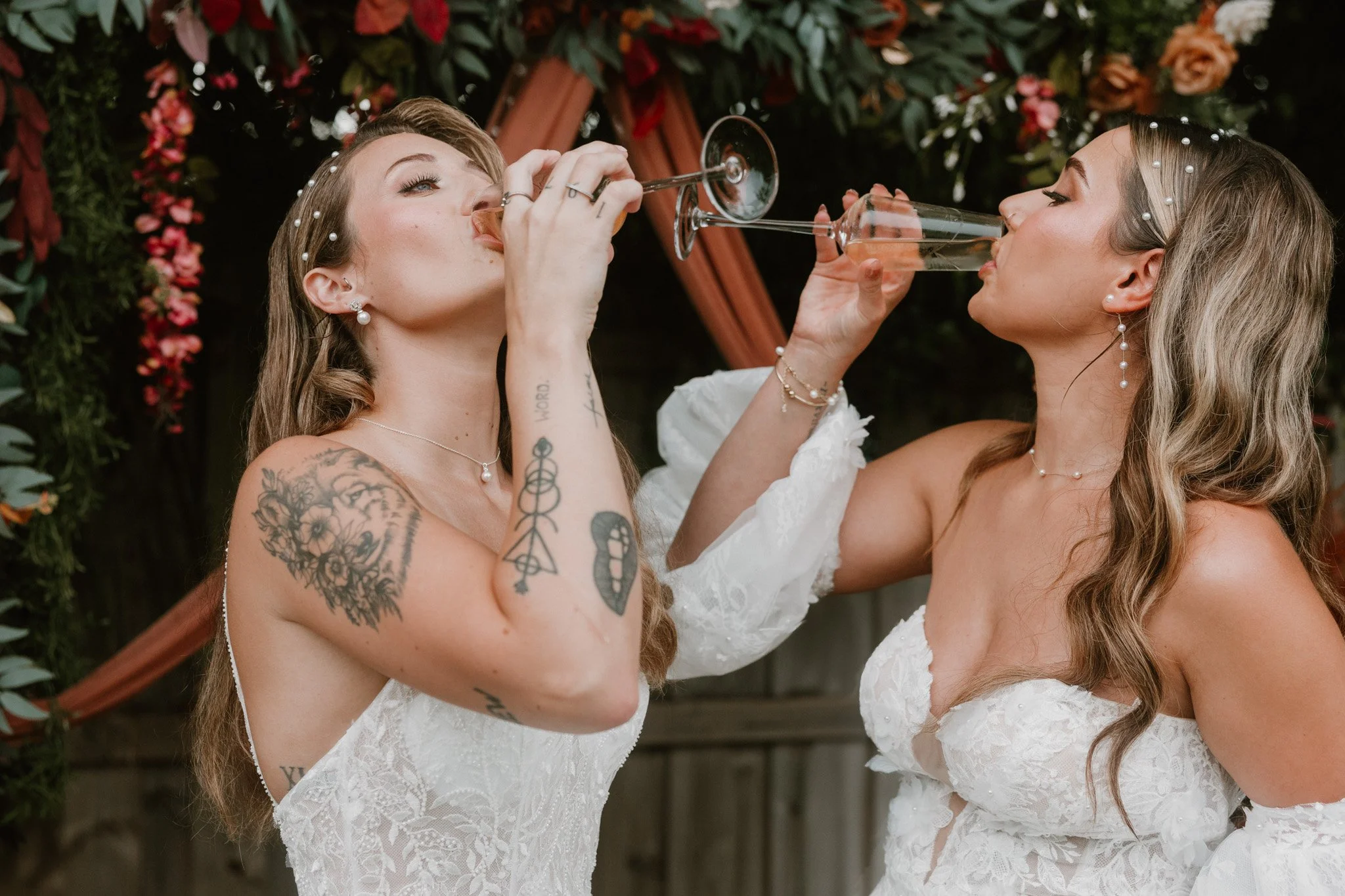 Queer couple share champagne on their elopement day, standing at their homemade alter in the backyard of an airbnb in Florida