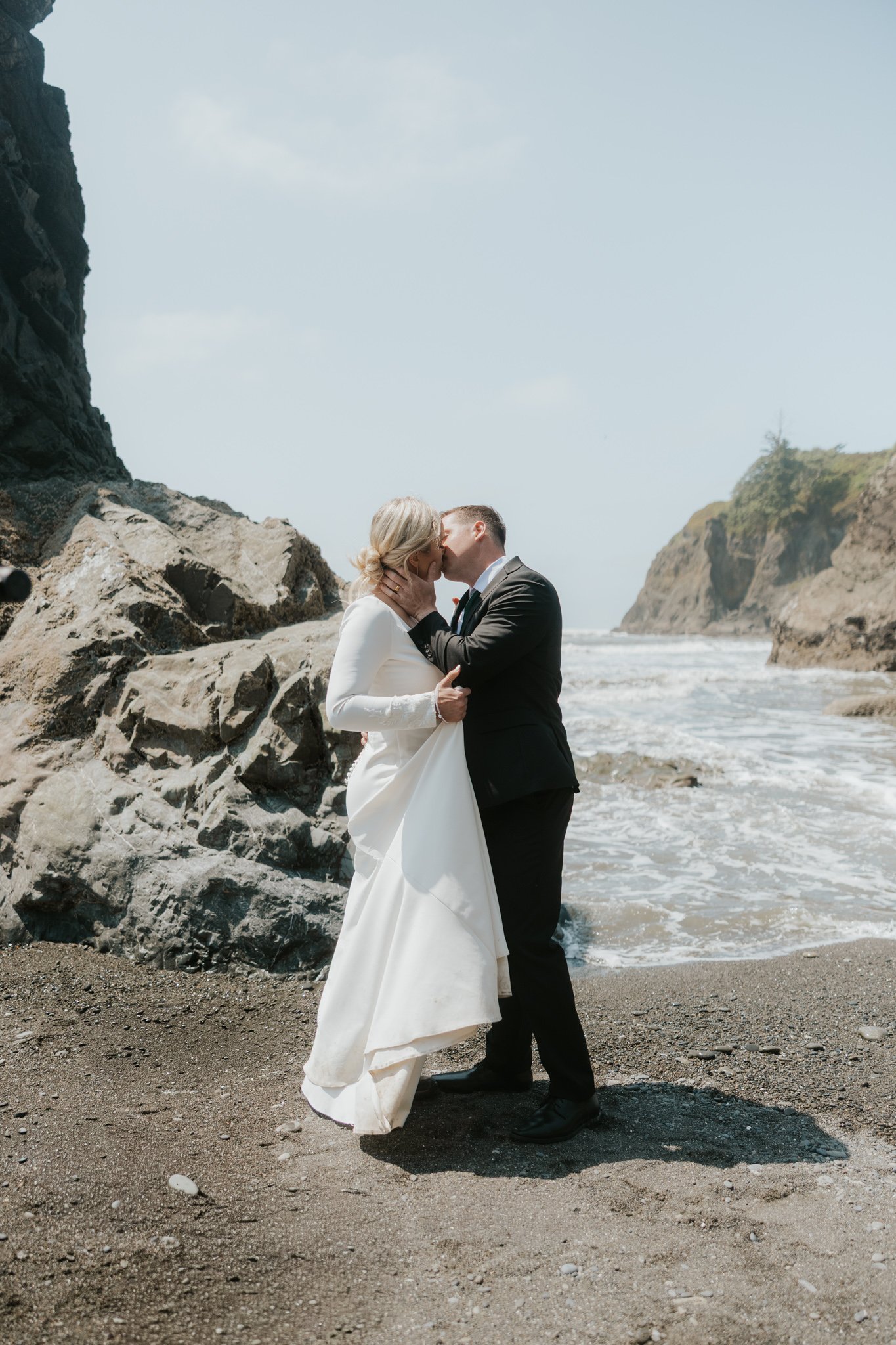A couple in wedding attire kissing on Ruby Beach in Olympic National Park.
