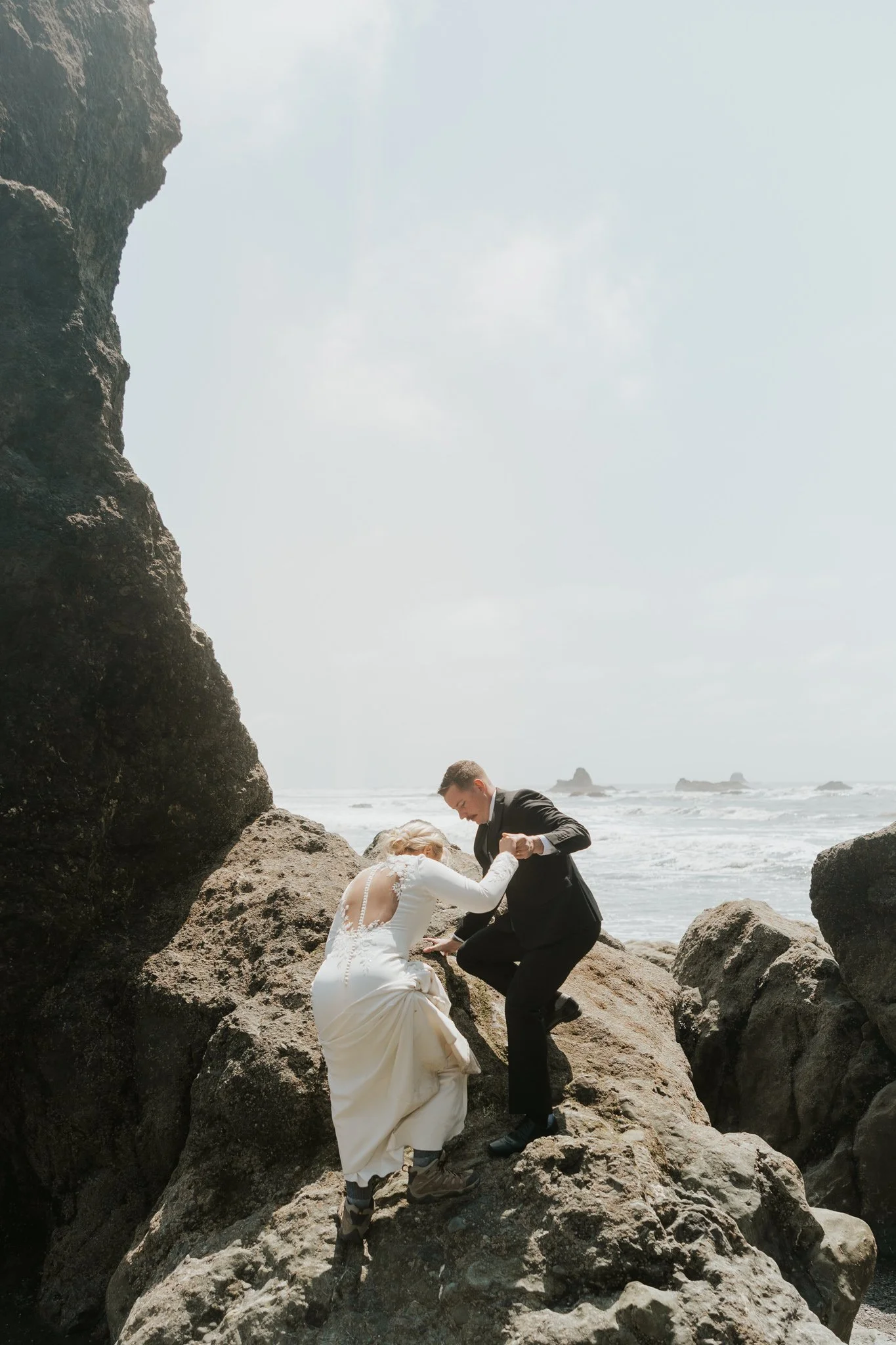 Couple climbs a rock at Ruby Beach in Olympic National Park at sunrise