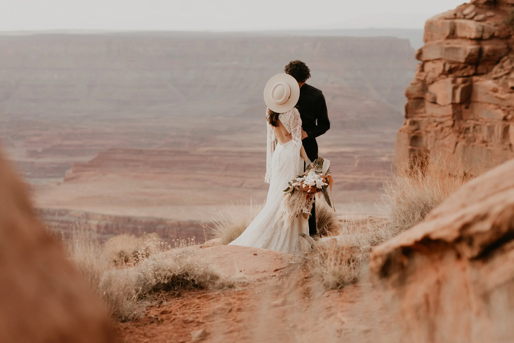boho couple shares a kiss on the rocky edge of Dead Horse Point State Park