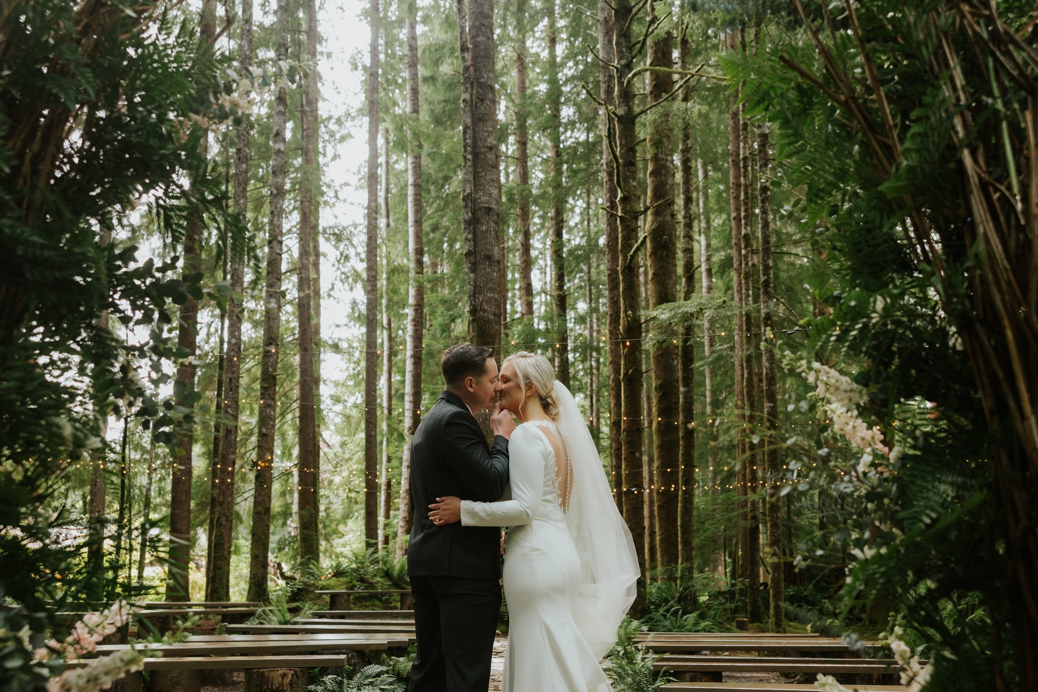 A wedding couple kisses under a mossy canopy at the Ferns Acres wedding venue in Olympic National Park