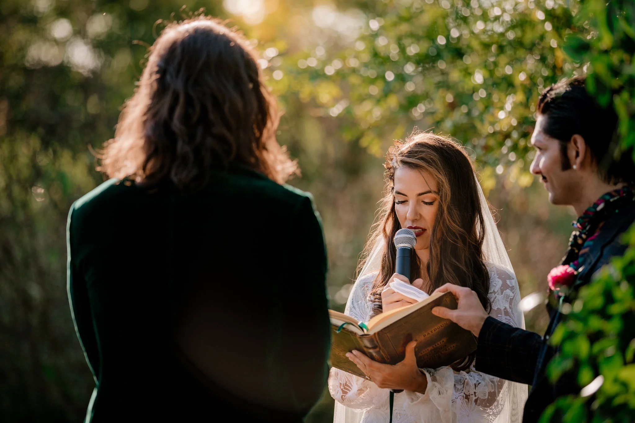 Lindsey speaks her vows to Dune as the sun sets through the trees behind her.