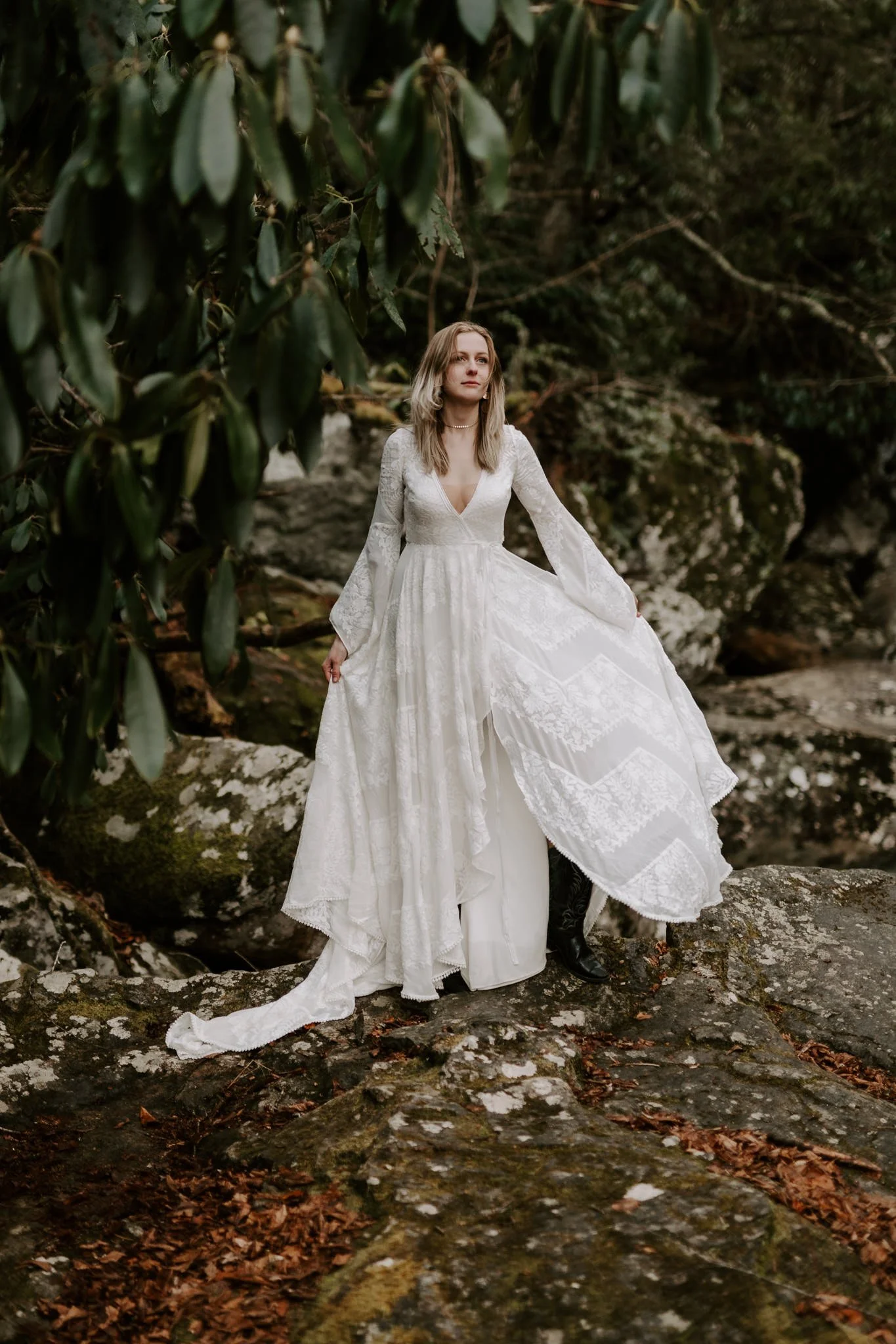 A bridge stands on a rocky ledge and moves her dress back and forth