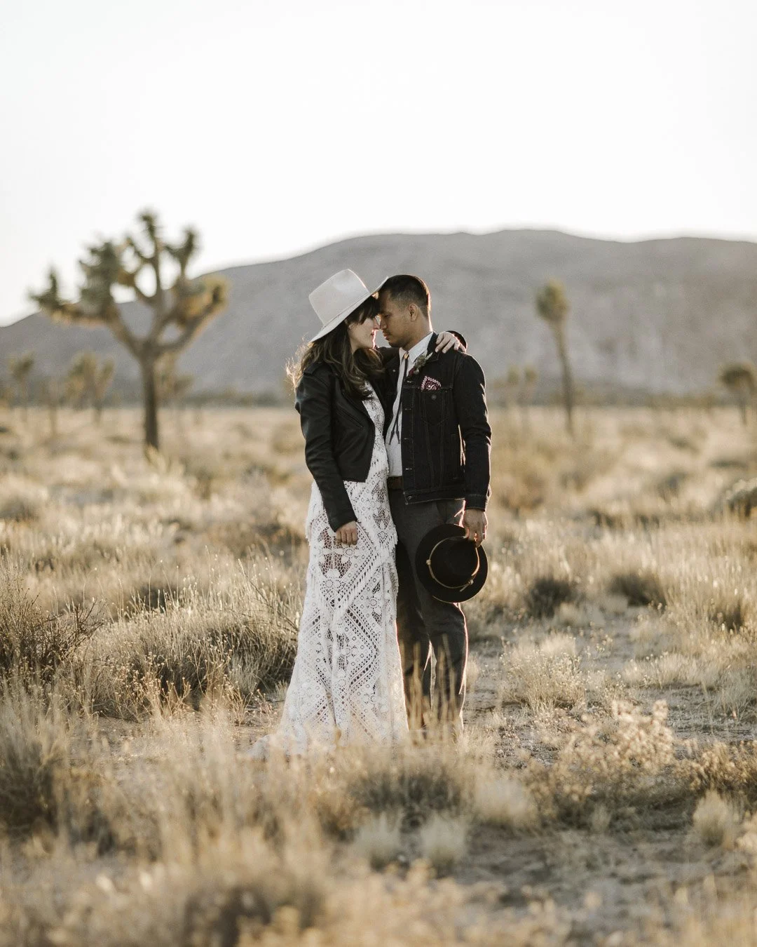 couple stands forehead to forehead as the sun sets in Joshua Tree National Park