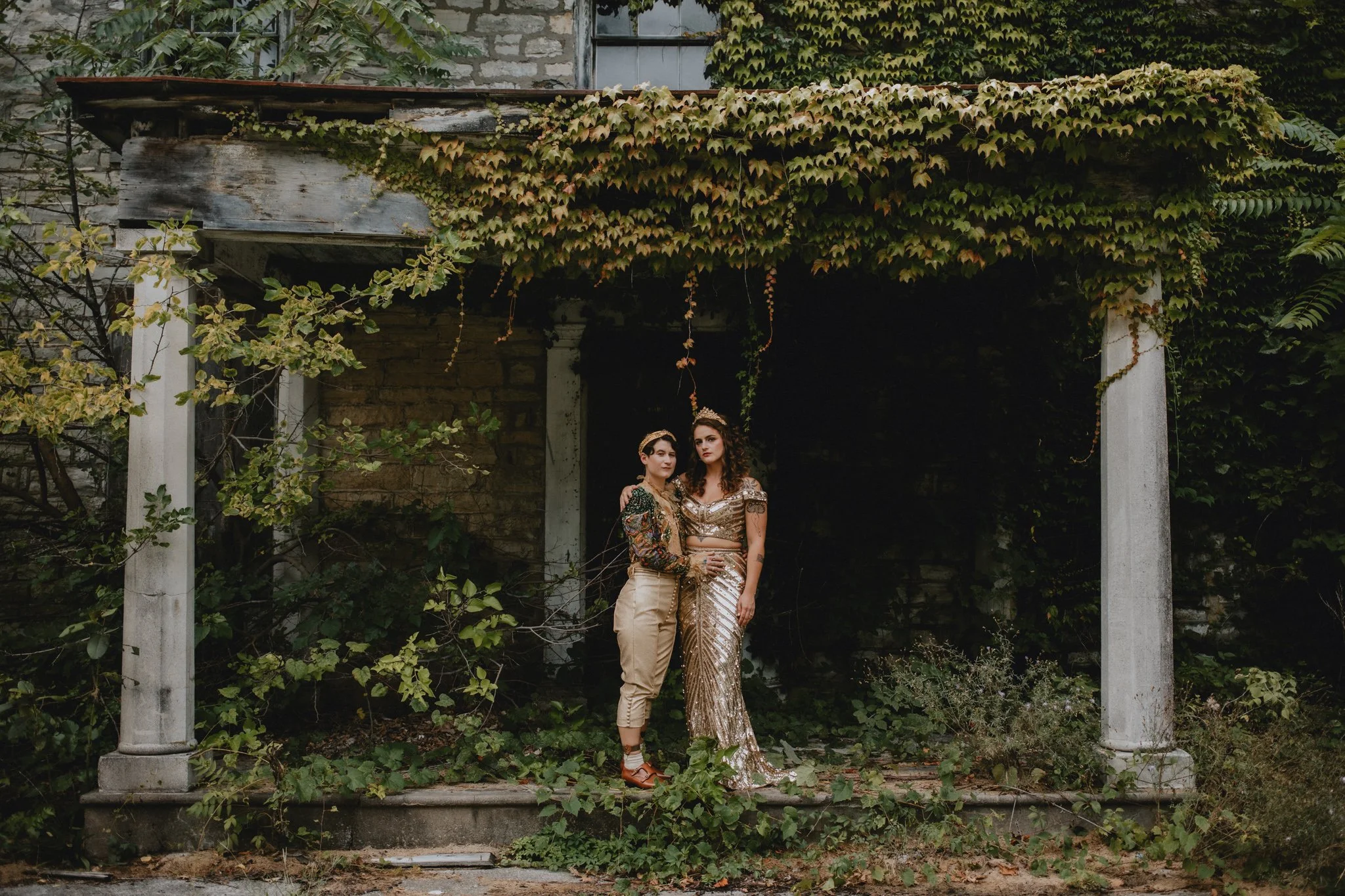 Wedding couple stands on the porch of an ivy-covered abandoned building