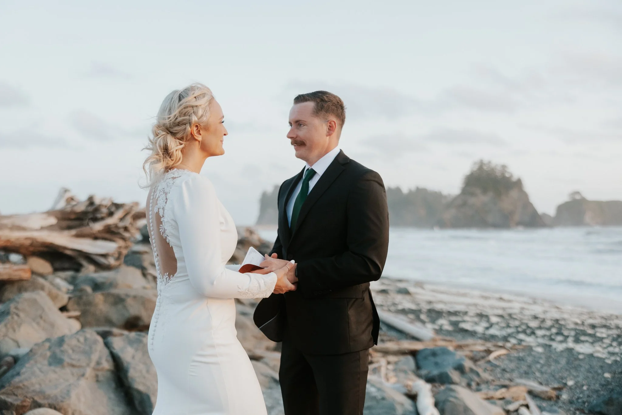 A wedding couple shares vows on the rocky coastline of Rialto Beach in Olympic National Park