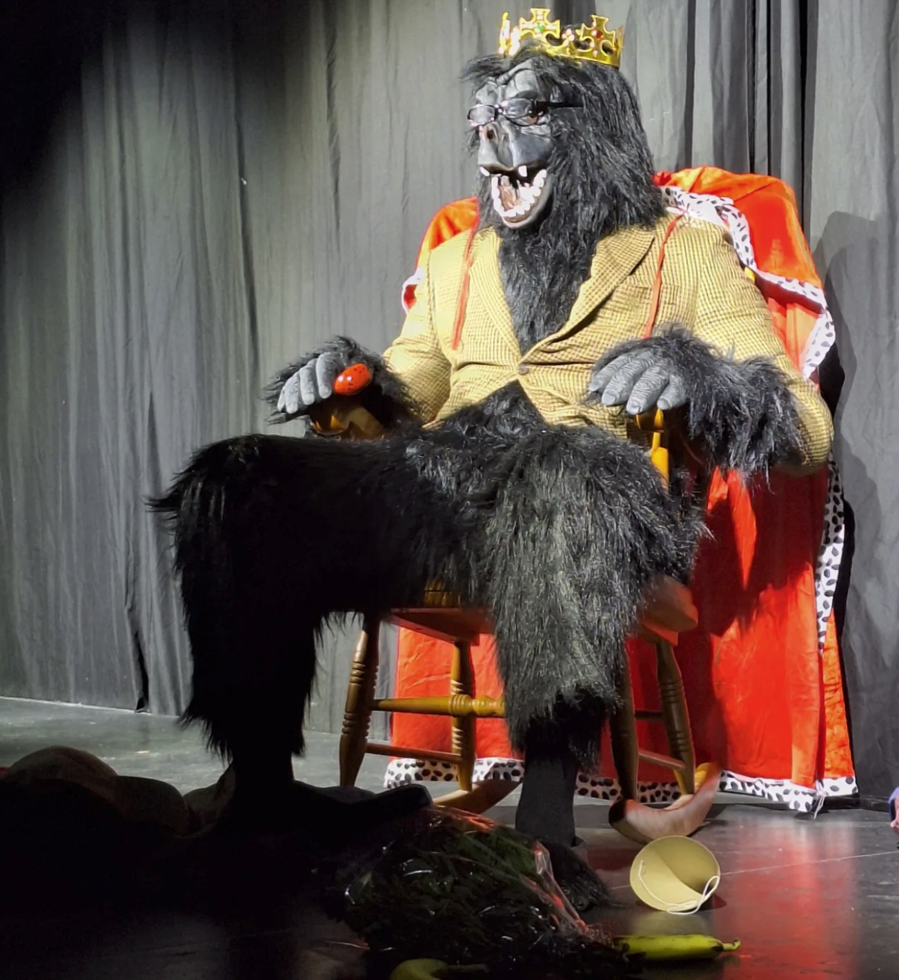 A YOUNG MAN DRESSED AS A GORILLA DRESSED AS AN OLD MAN SITS ROCKING IN....
