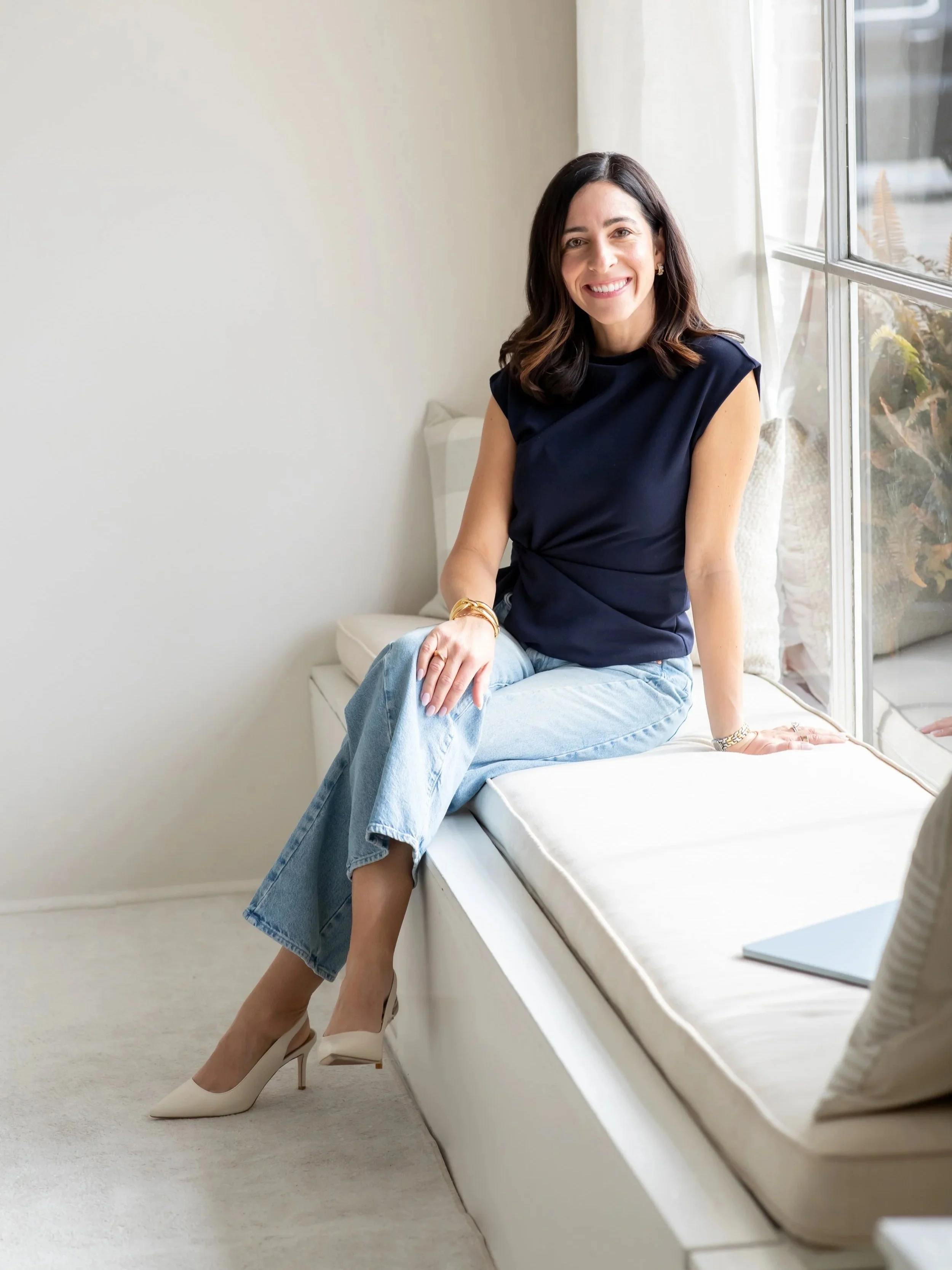 Kristin Wood sitting on a bench near a window, personal stylist and color analysis consultant.