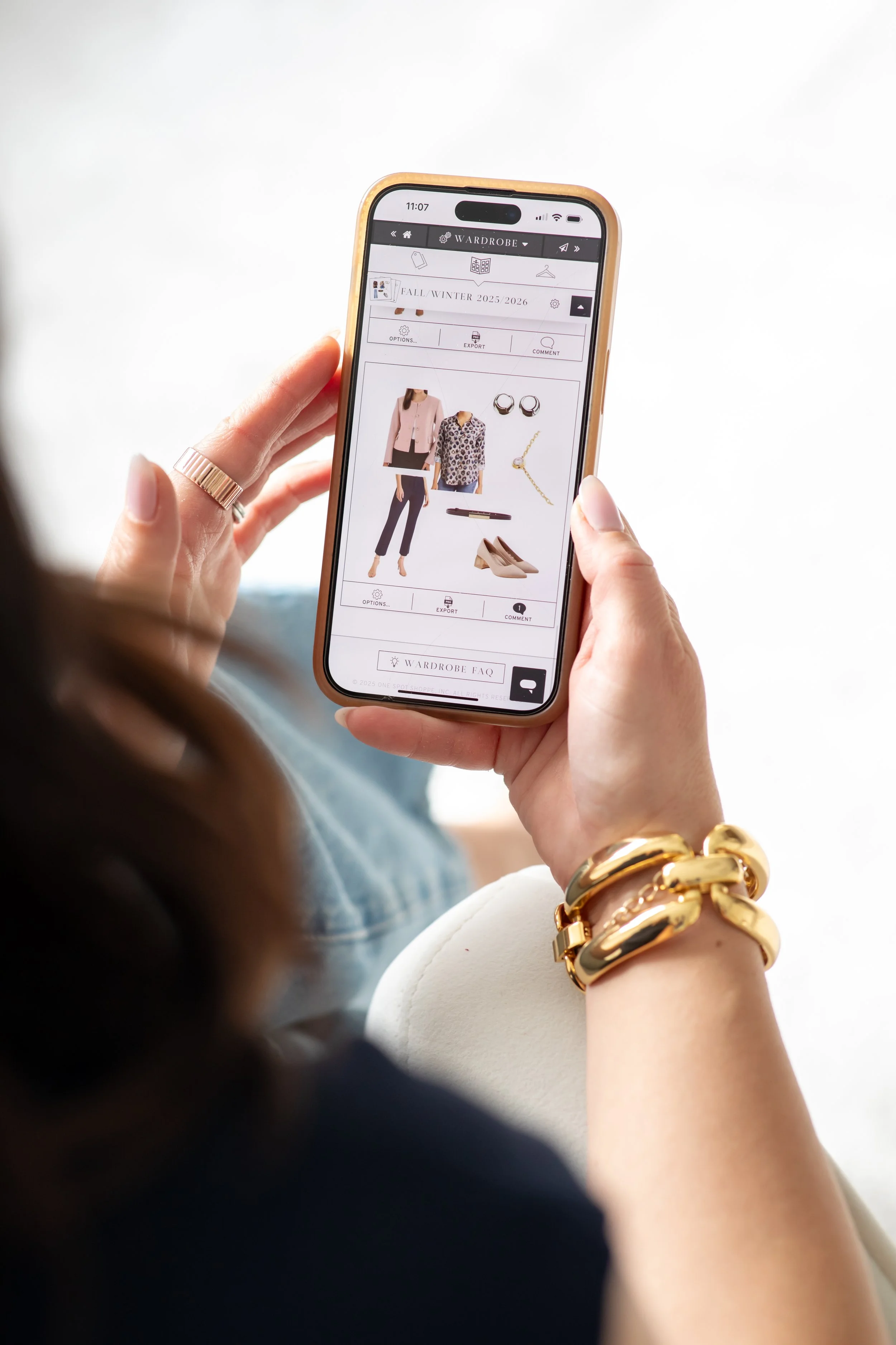 Kristin Wood holding a phone showing her private styling app for outfit planning and shopping support.