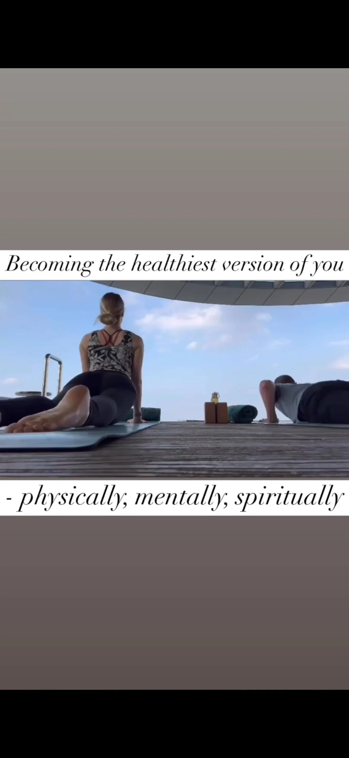 People practicing yoga outdoors on a wooden deck against a blue sky with clouds, with yoga mats and towels nearby, and inspirational text overlay about becoming the healthiest version of oneself physically, mentally, and spiritually.