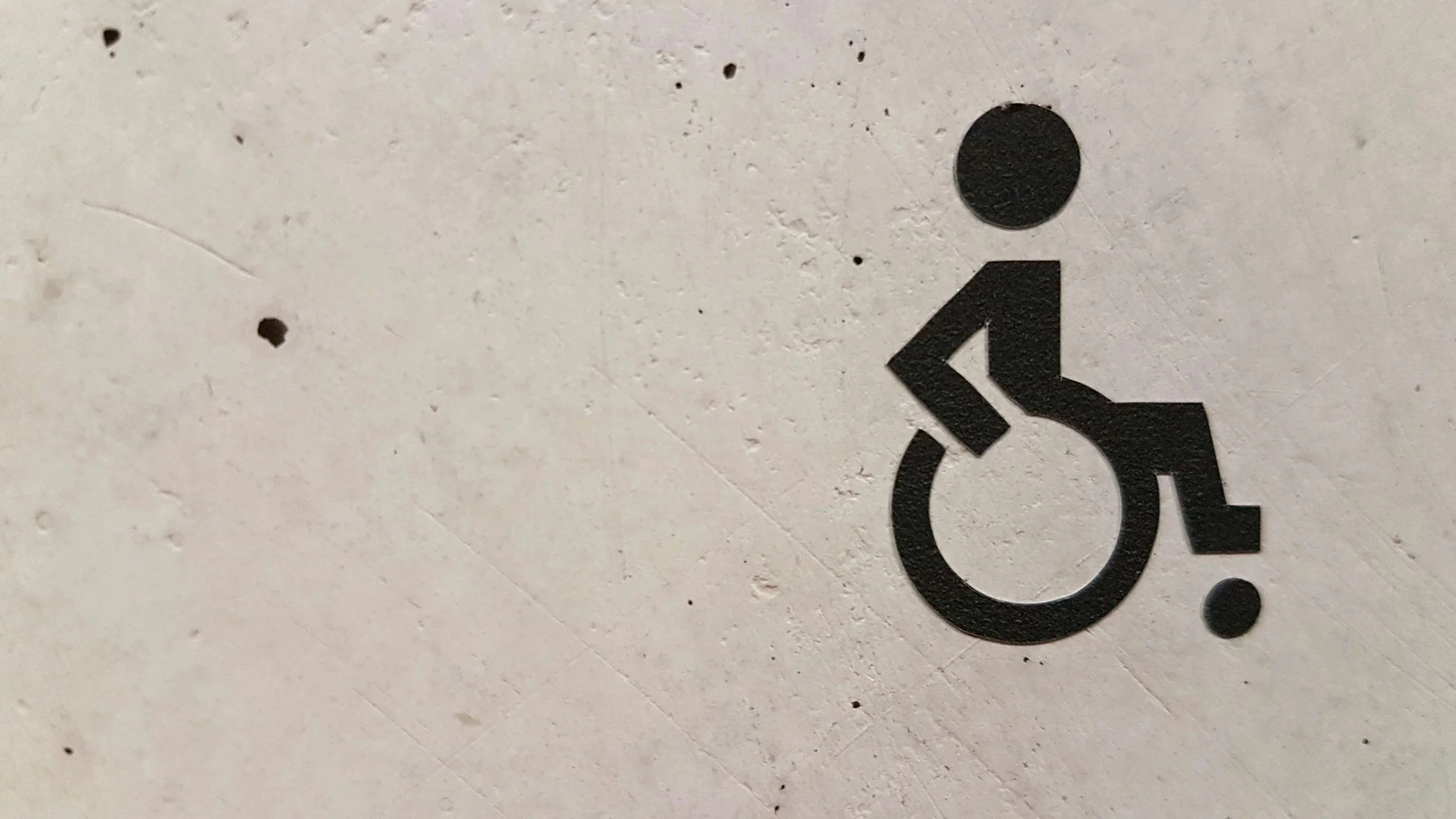 A stone wall with a black wheelchair graphic