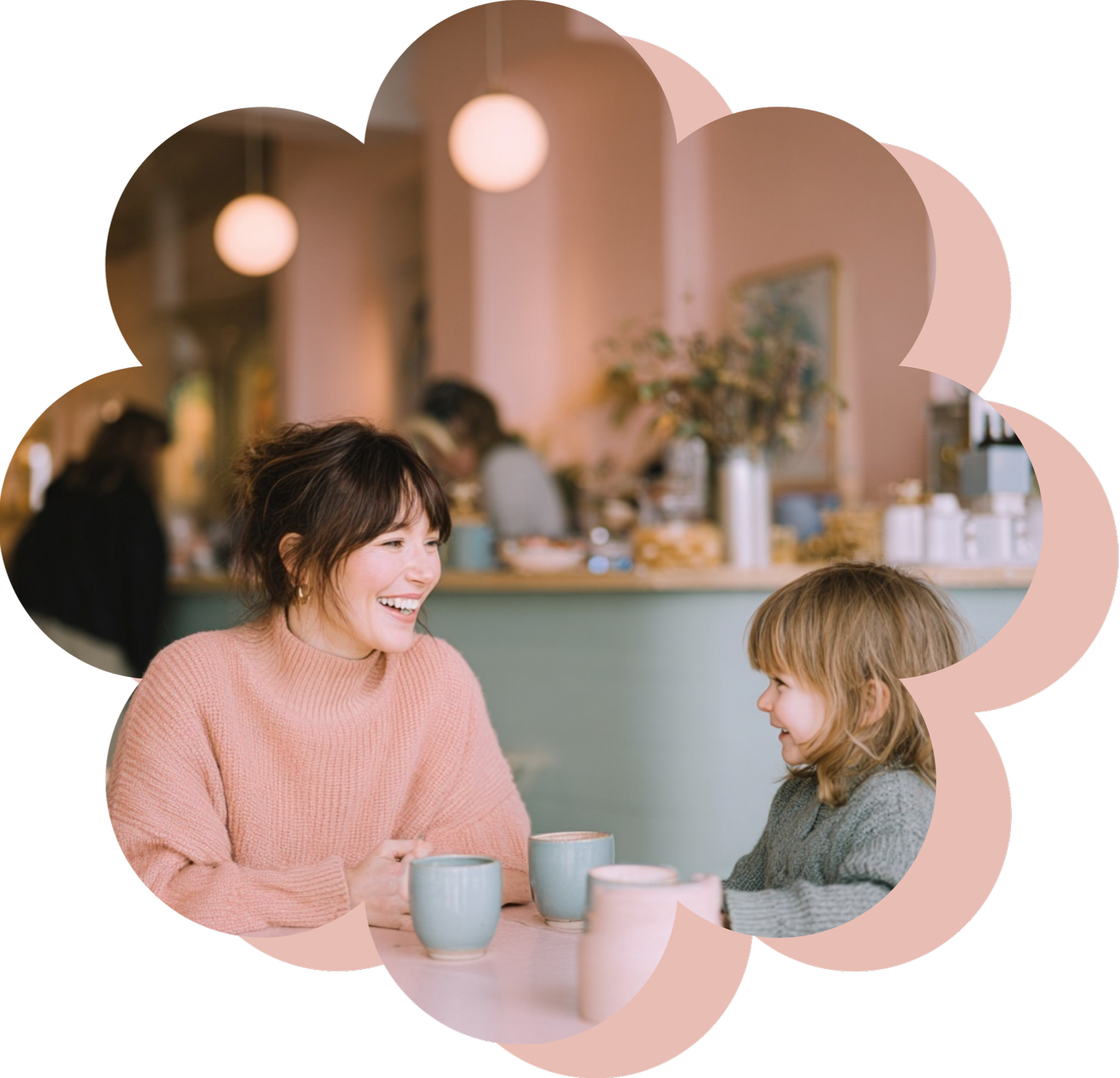 Woman and girl enjoying a conversation at a cafe table with coffee mugs.