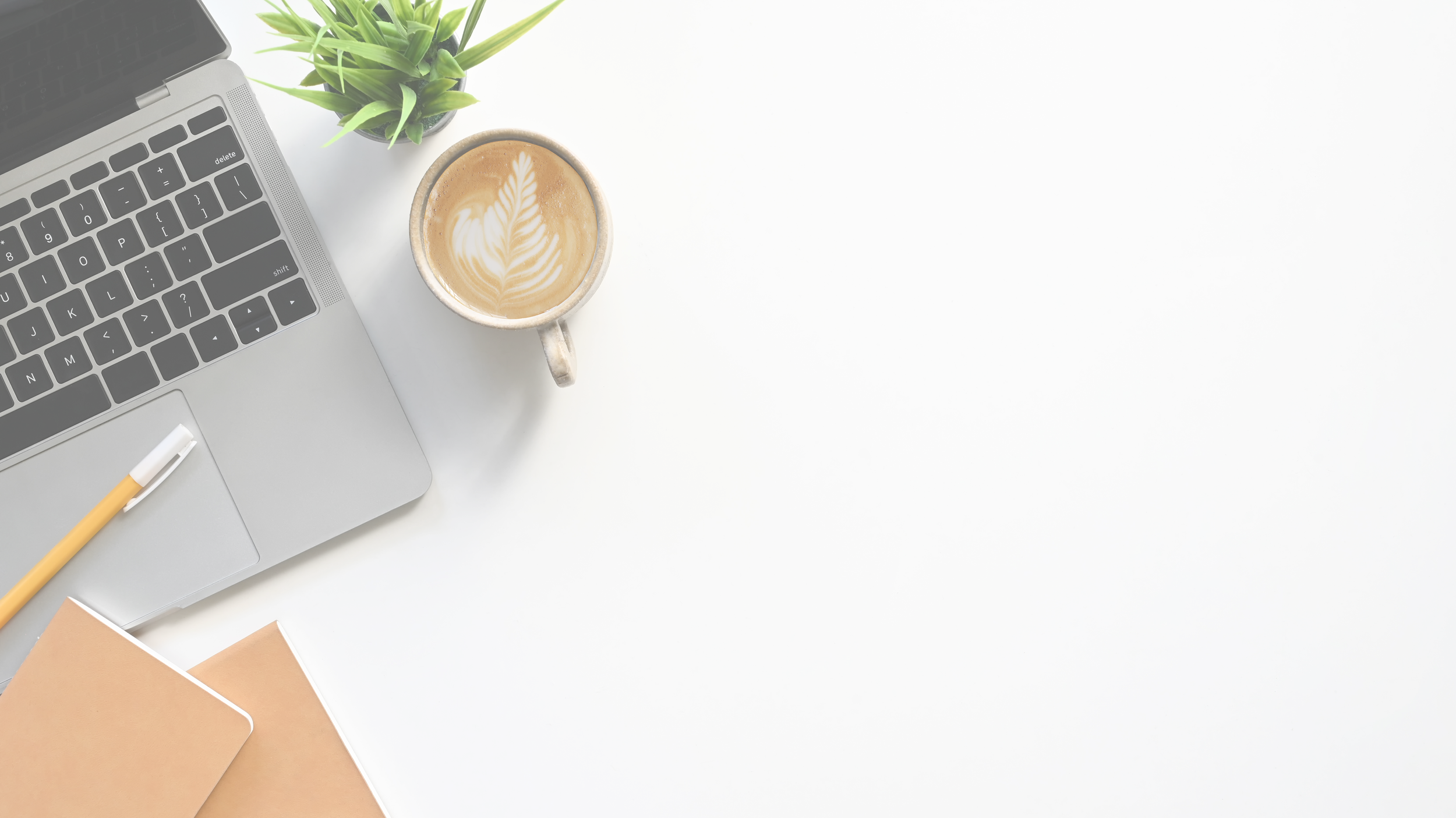 A workspace with a laptop, a cup of coffee with latte art, a small potted plant, a yellow pen, and some brown notebooks on a white desk.