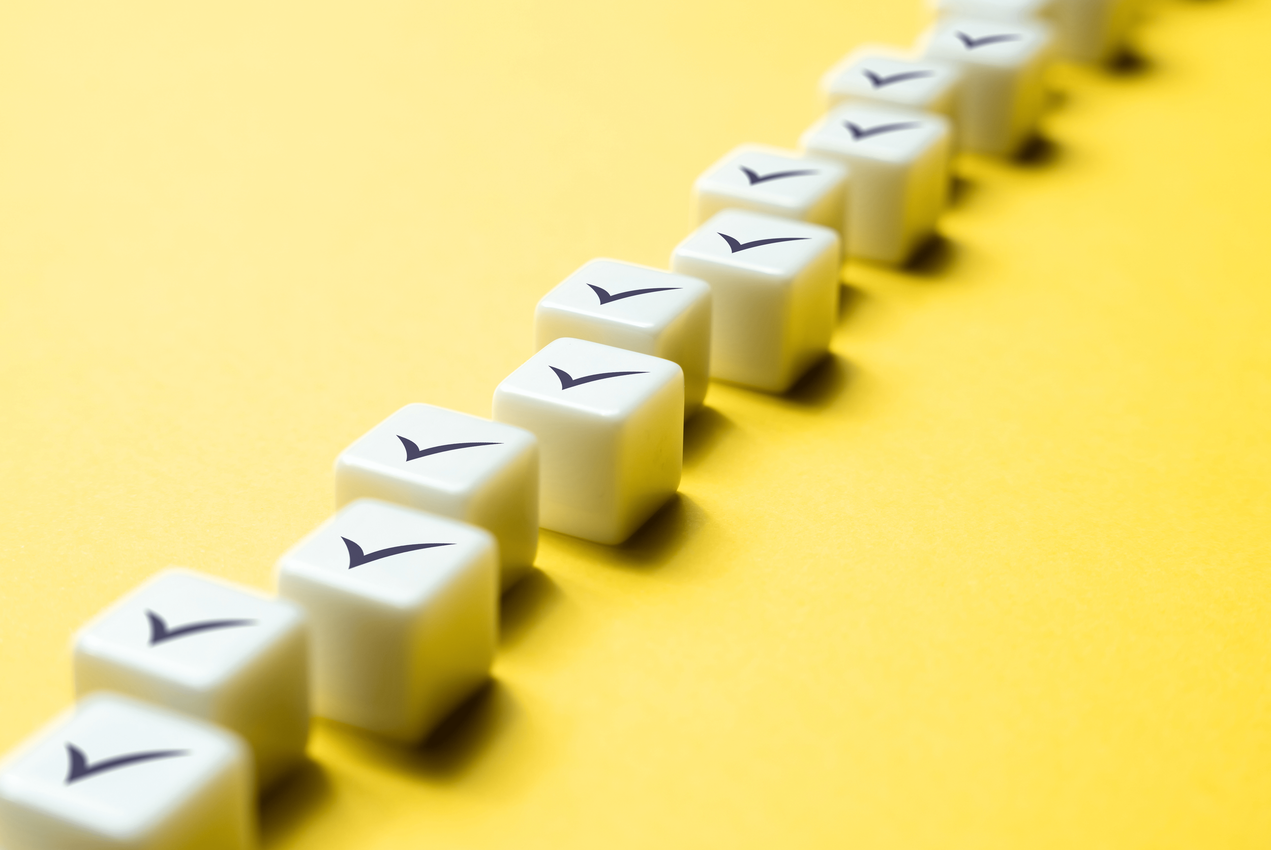 Line of white dice with a check mark on each side, set against a yellow background.