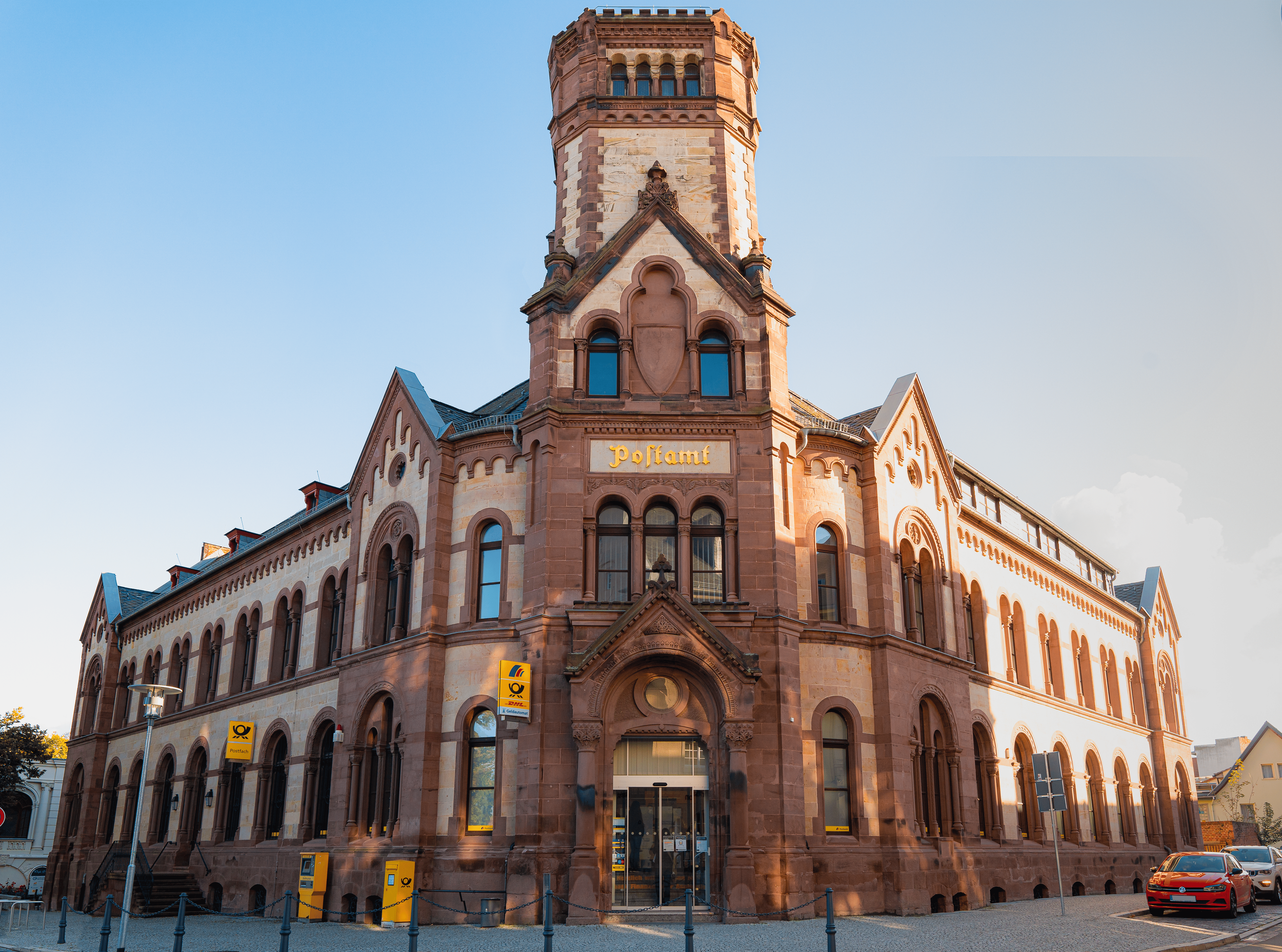 Historisches Gebäude mit Wasserwacht-Station, mit Uhrturm auf der Fassade, in rotem Sandstein gebaut, bei Sonnenuntergang, mit Autos vor dem Eingang, in Deutschland.