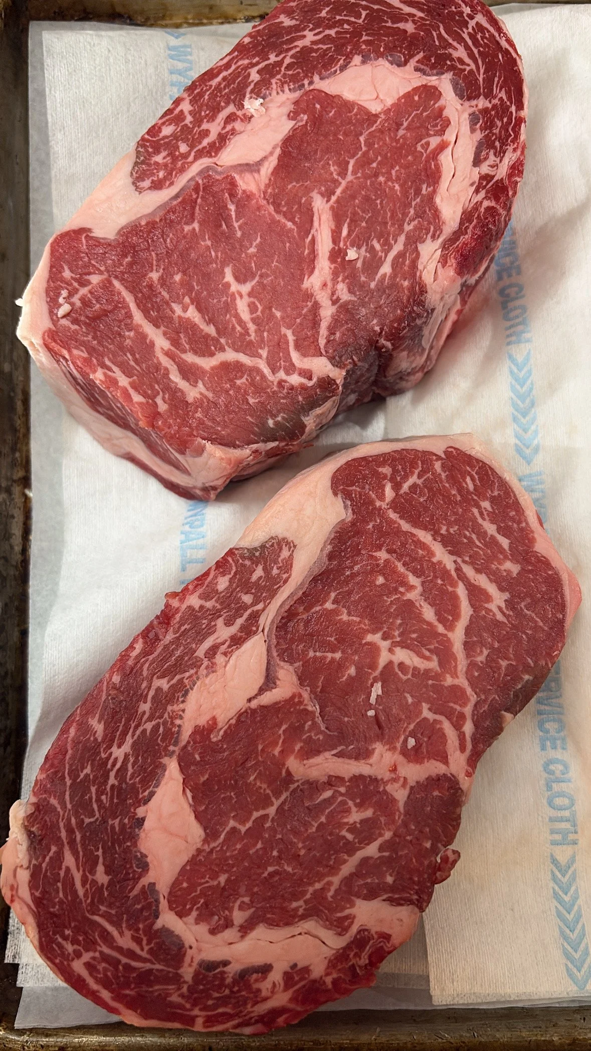 Two raw, marbled beef steaks placed on a sheet of butcher paper.