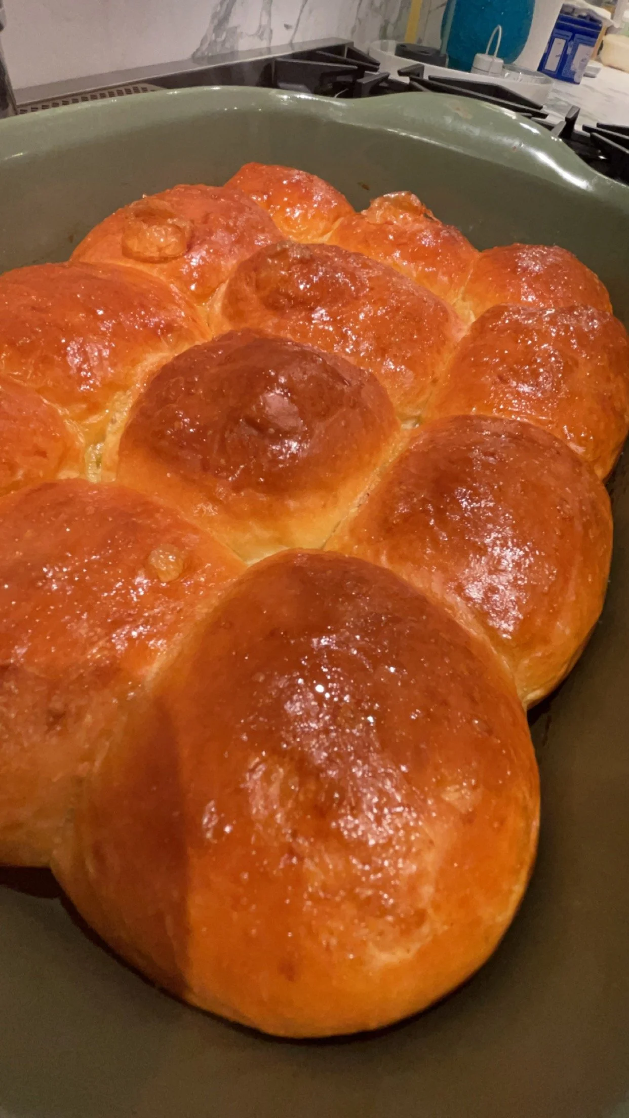 Freshly baked golden-brown bread rolls in a green baking dish.