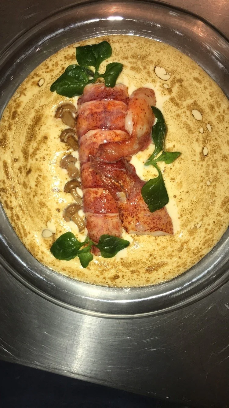 Baked chicken wrapped in bacon, garnished with green herbs, in a cream-based sauce with sliced mushrooms, in a glass dish.