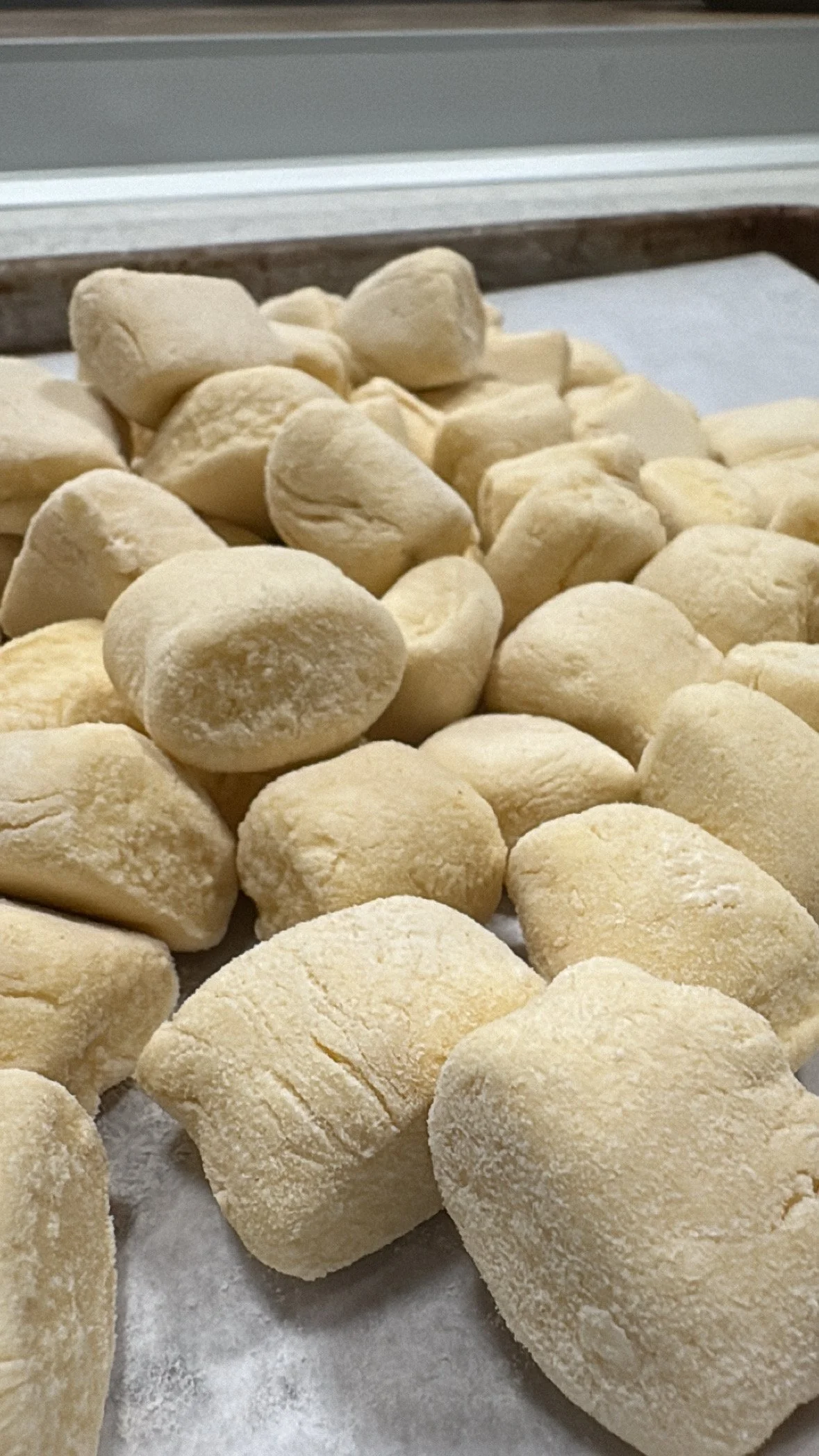 Close-up of uncooked gnocchi resting on a baking sheet.
