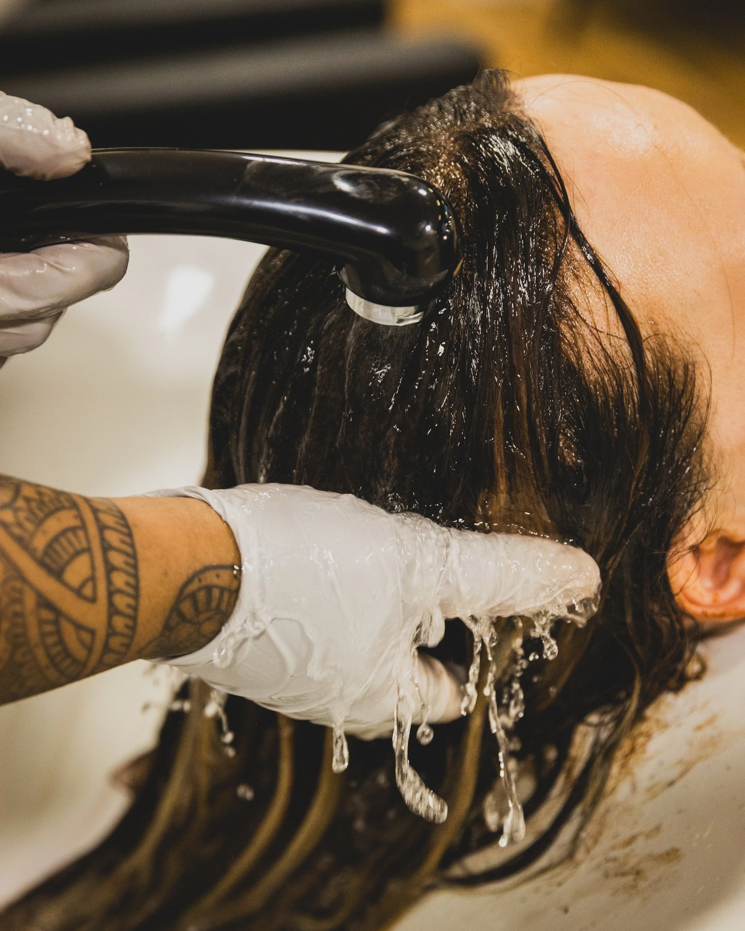 Hair Stylist offering a conditioning treatment and washing hair in a basin with water.