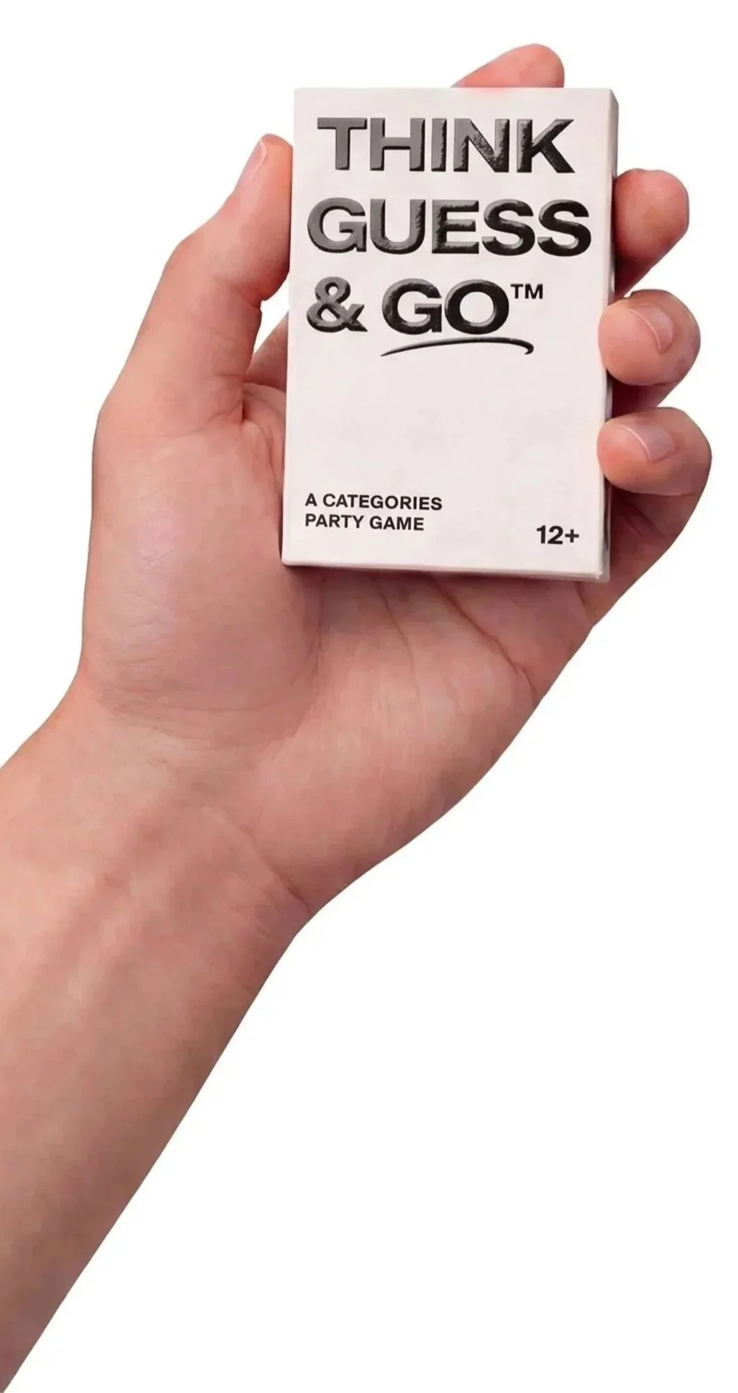 A person holding a small box with the words "THINK GUESS & GO" printed on it, and additional text indicating it is a party card game for ages 12 and up.