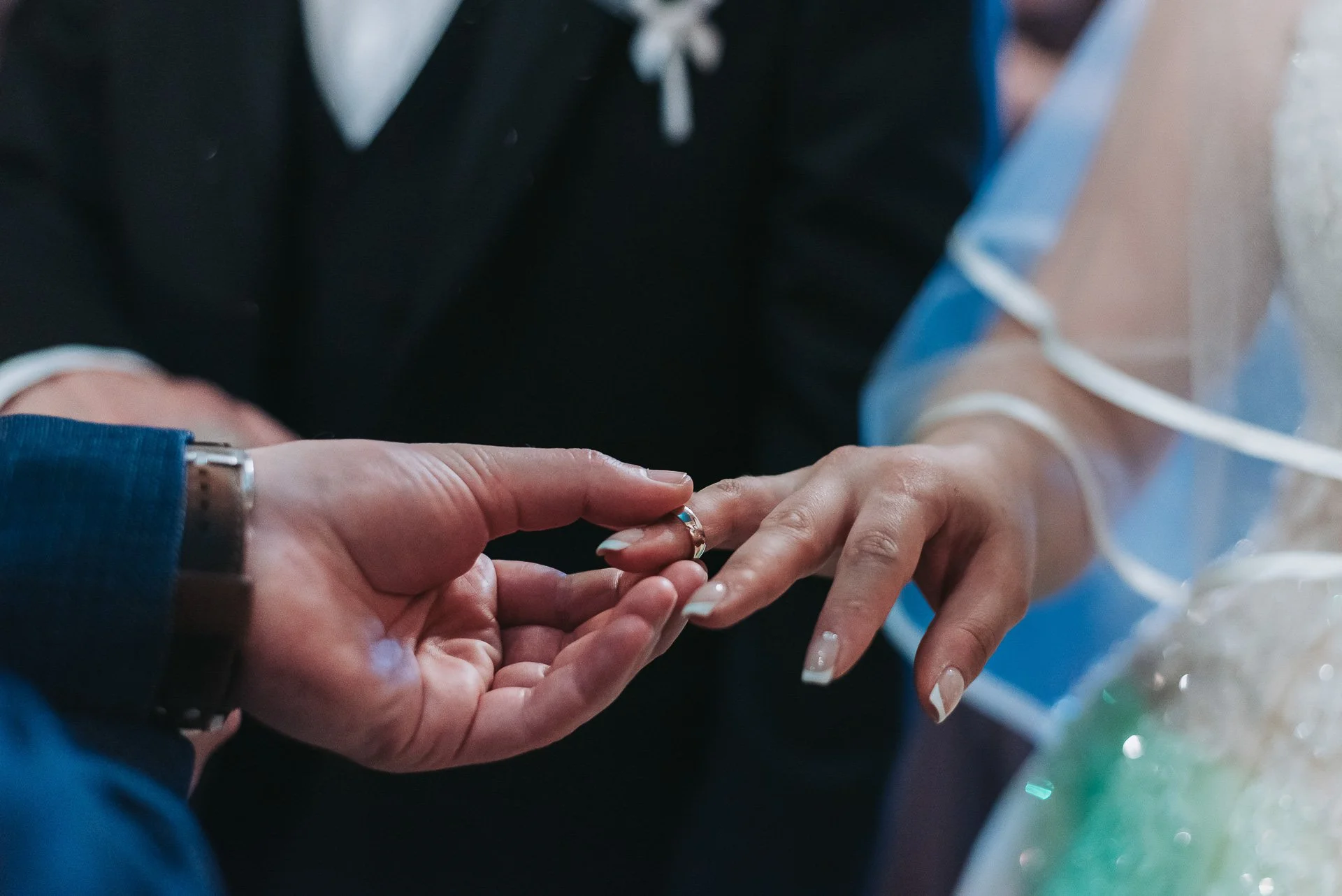 A man is placing a ring on a woman's finger during a wedding ceremony.