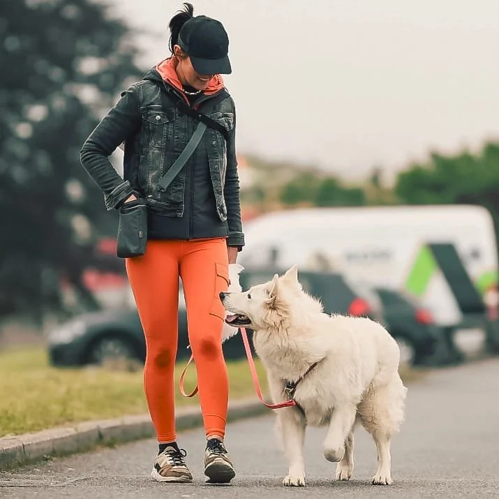 Une femme en tenue de sport avec un chien blanc lors d'une promenade