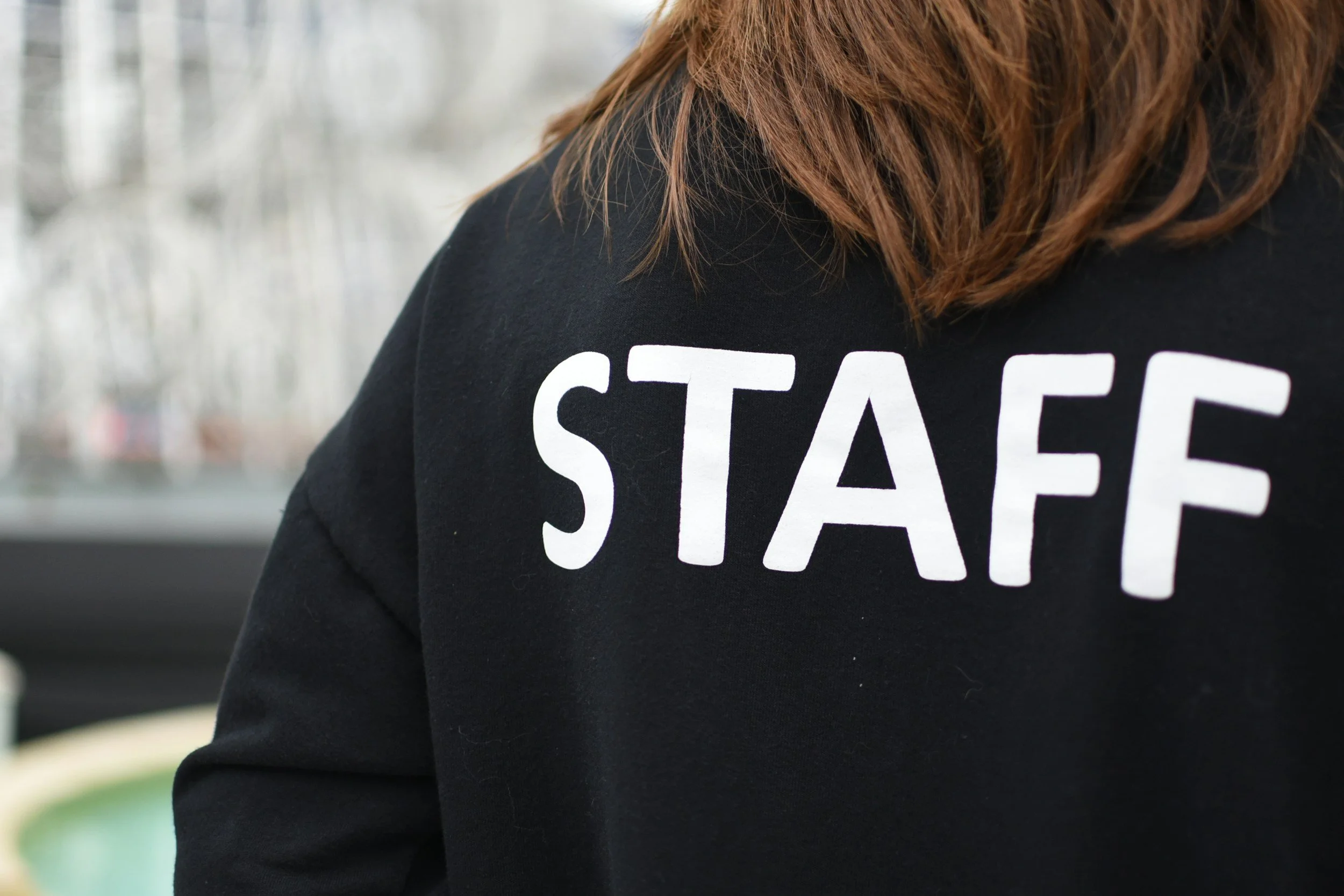 Close-up of a person wearing a black shirt with the word 'STAFF' printed in white letters on the back.