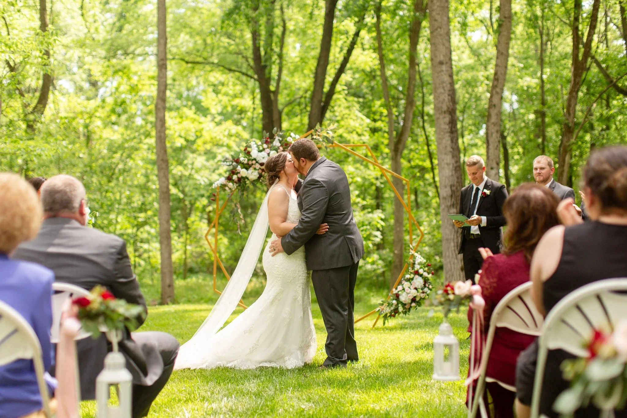 A forested outdoor setting beautifully surrounds the bride and groom and their guests.