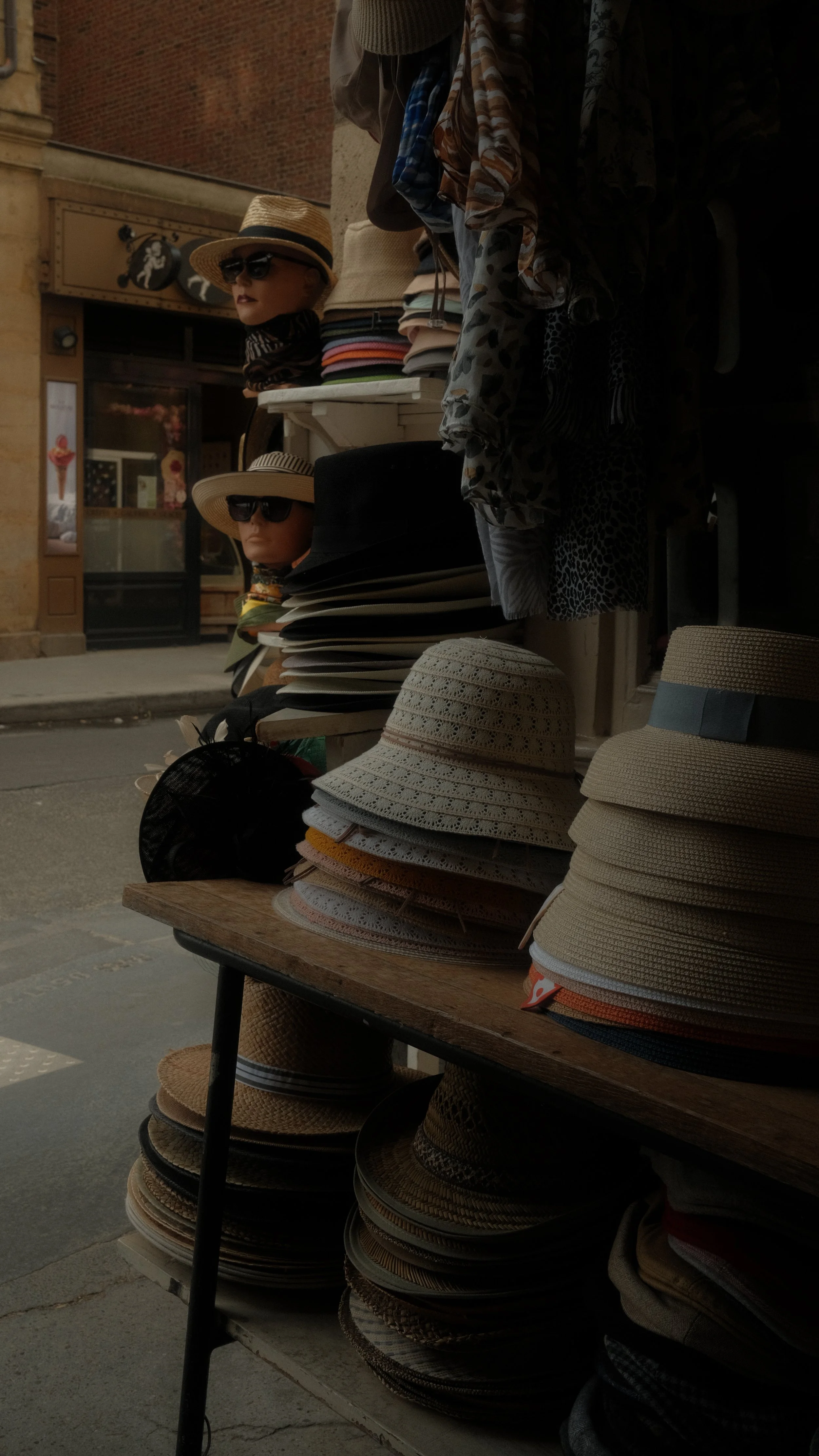 Vendeur de chapeaux avec une variété de chapeaux empilés sur une table et des paysages urbains en arrière-plan.