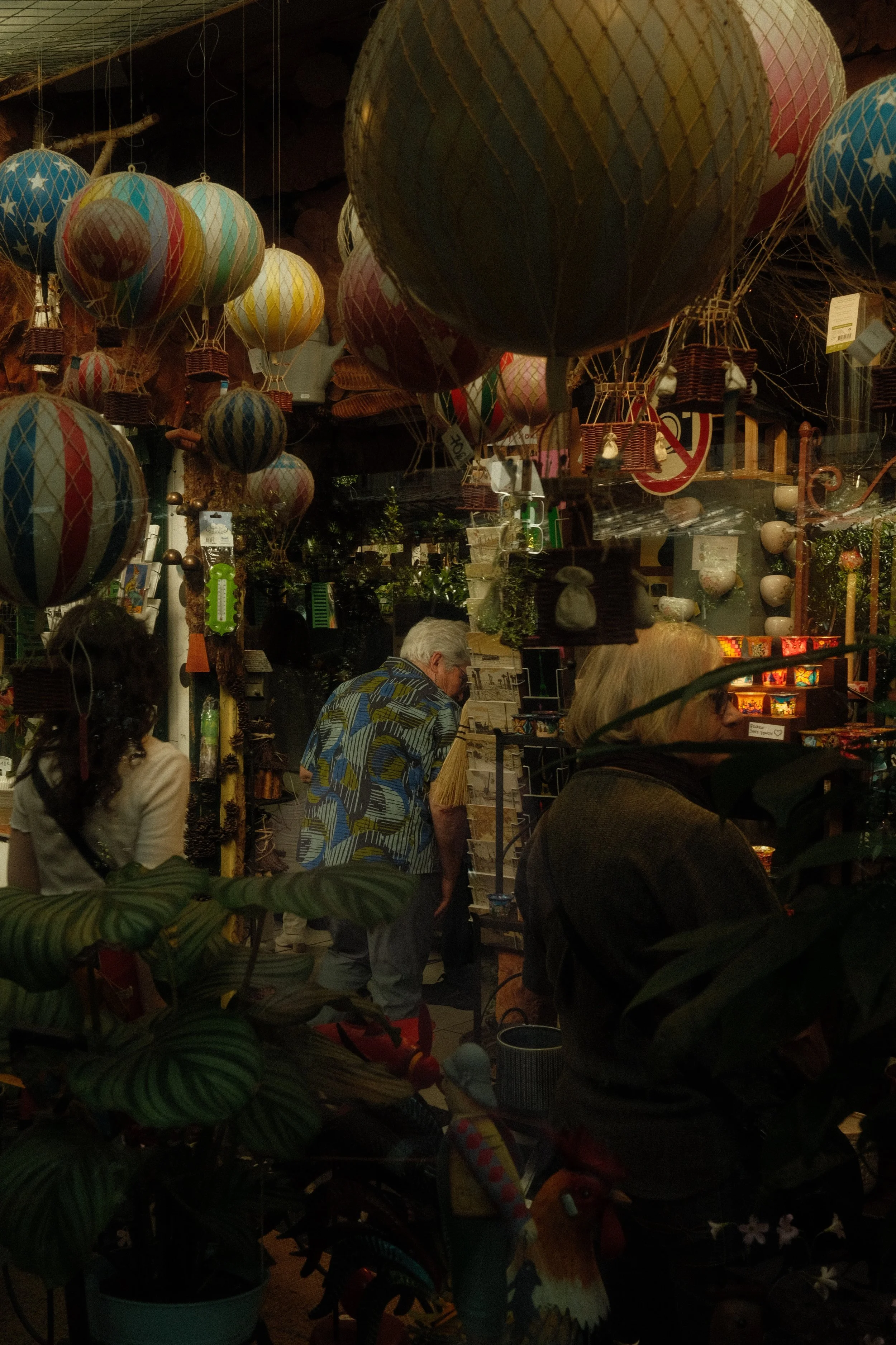 Vendeur et clients dans une boutique d'articles de décoration, avec des lampions colorés suspendus au plafond.