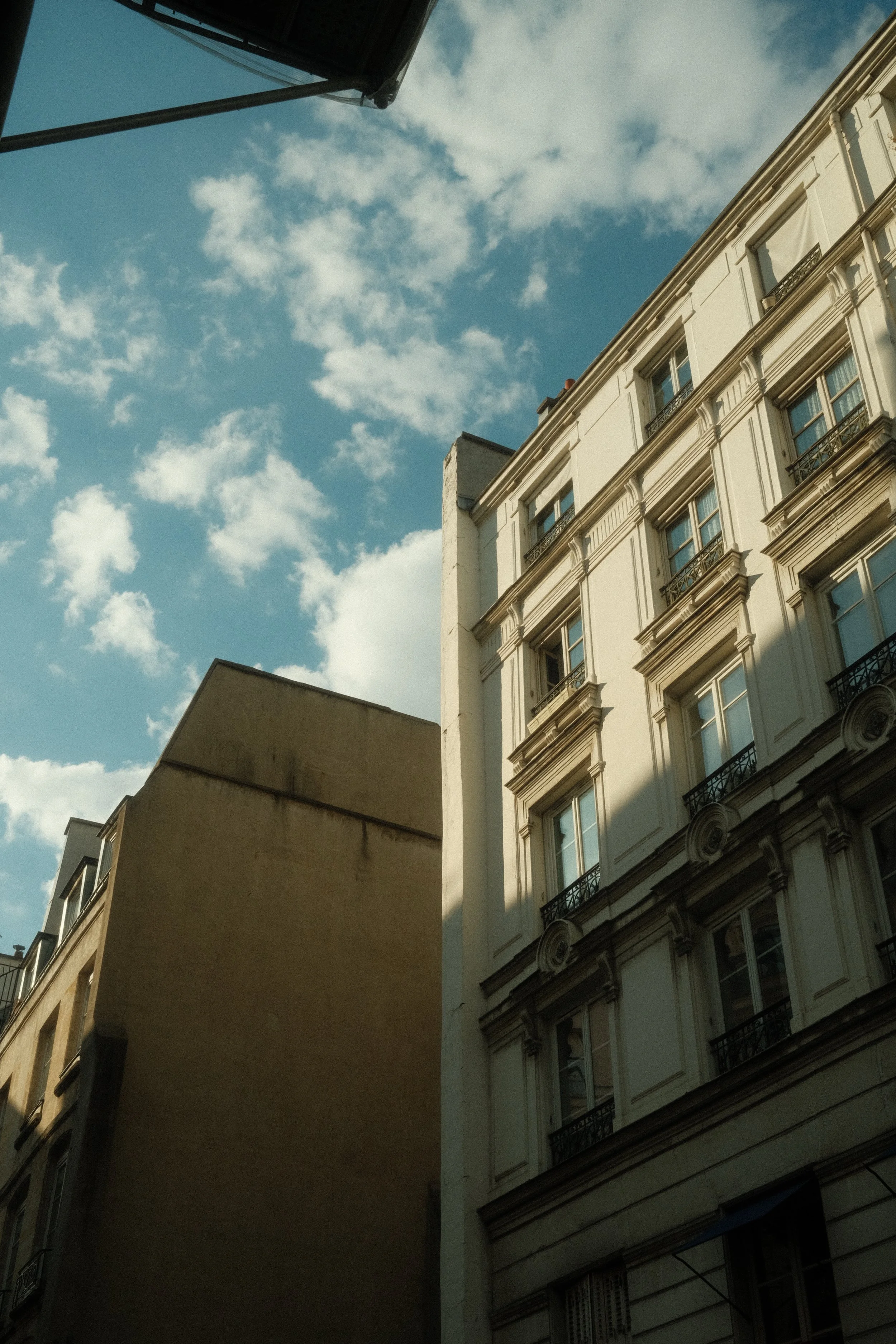Vue d'une rue urbaine avec des bâtiments anciens et modernes sous un ciel partiellement nuageux.