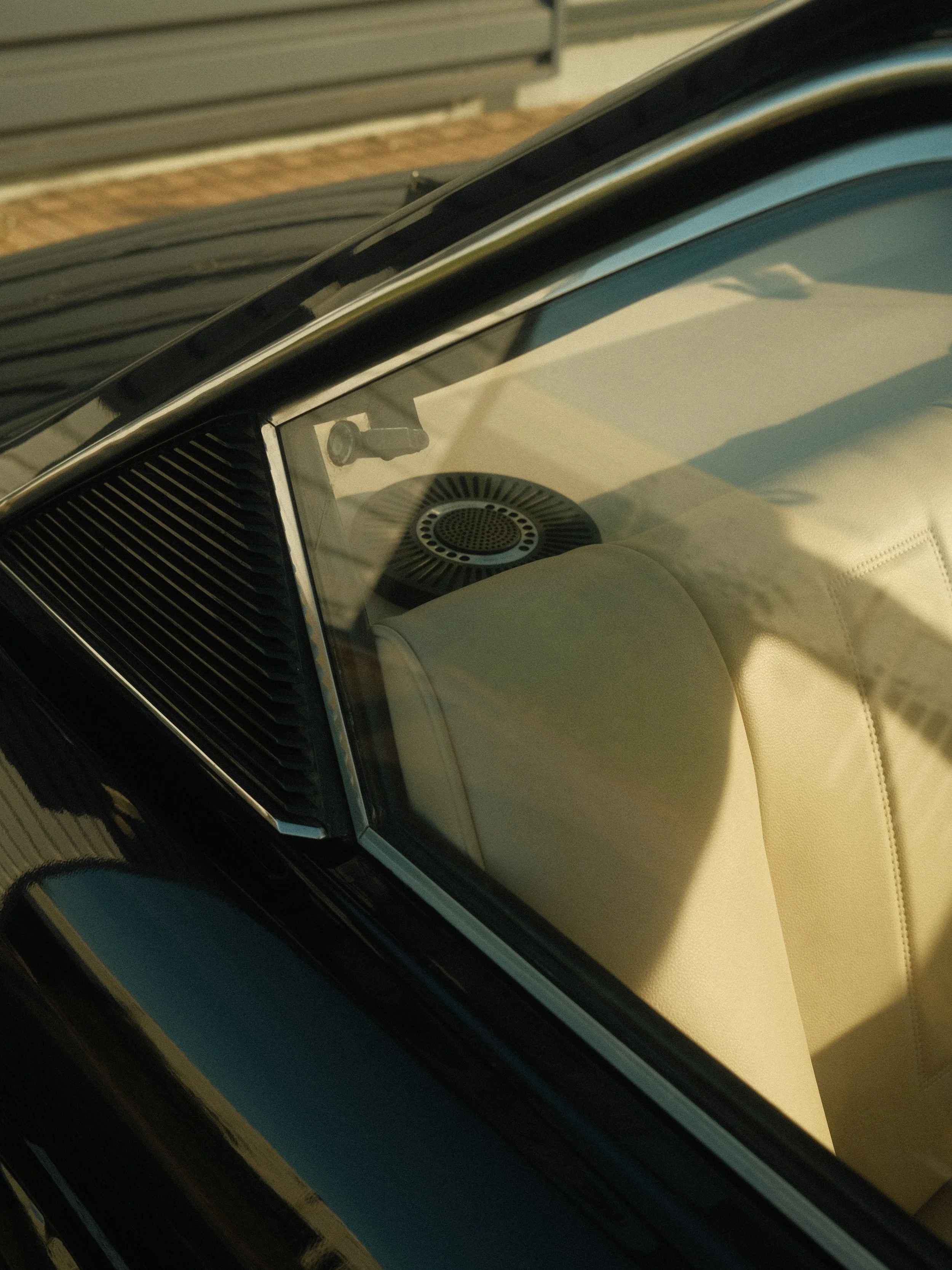 Vue intérieure d'une voiture vintage avec un pare-brise en verre, un haut-parleur rond et un panneau de commande.