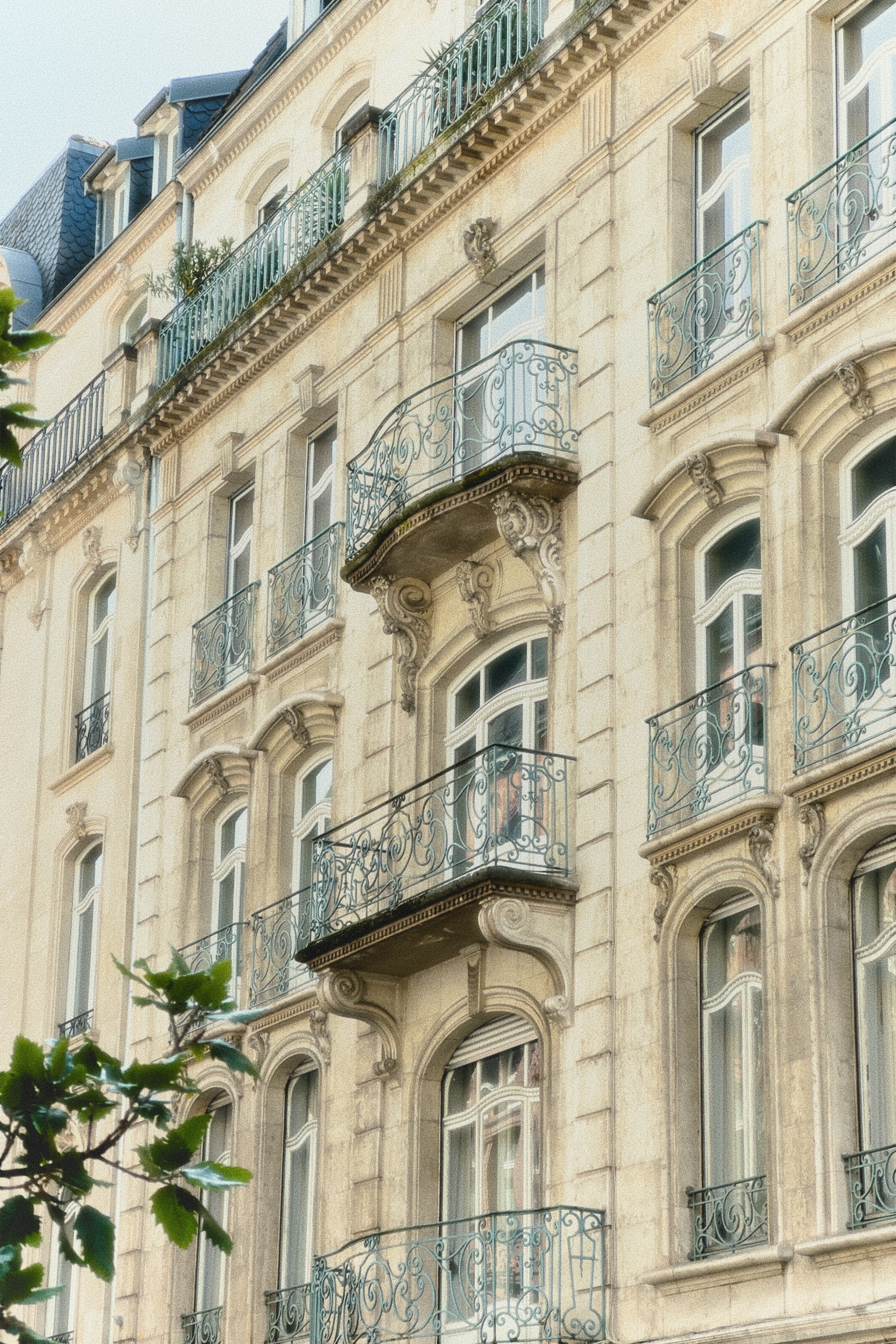 Façade d'un immeuble Haussmannien avec plusieurs balcons en fer forgé.
