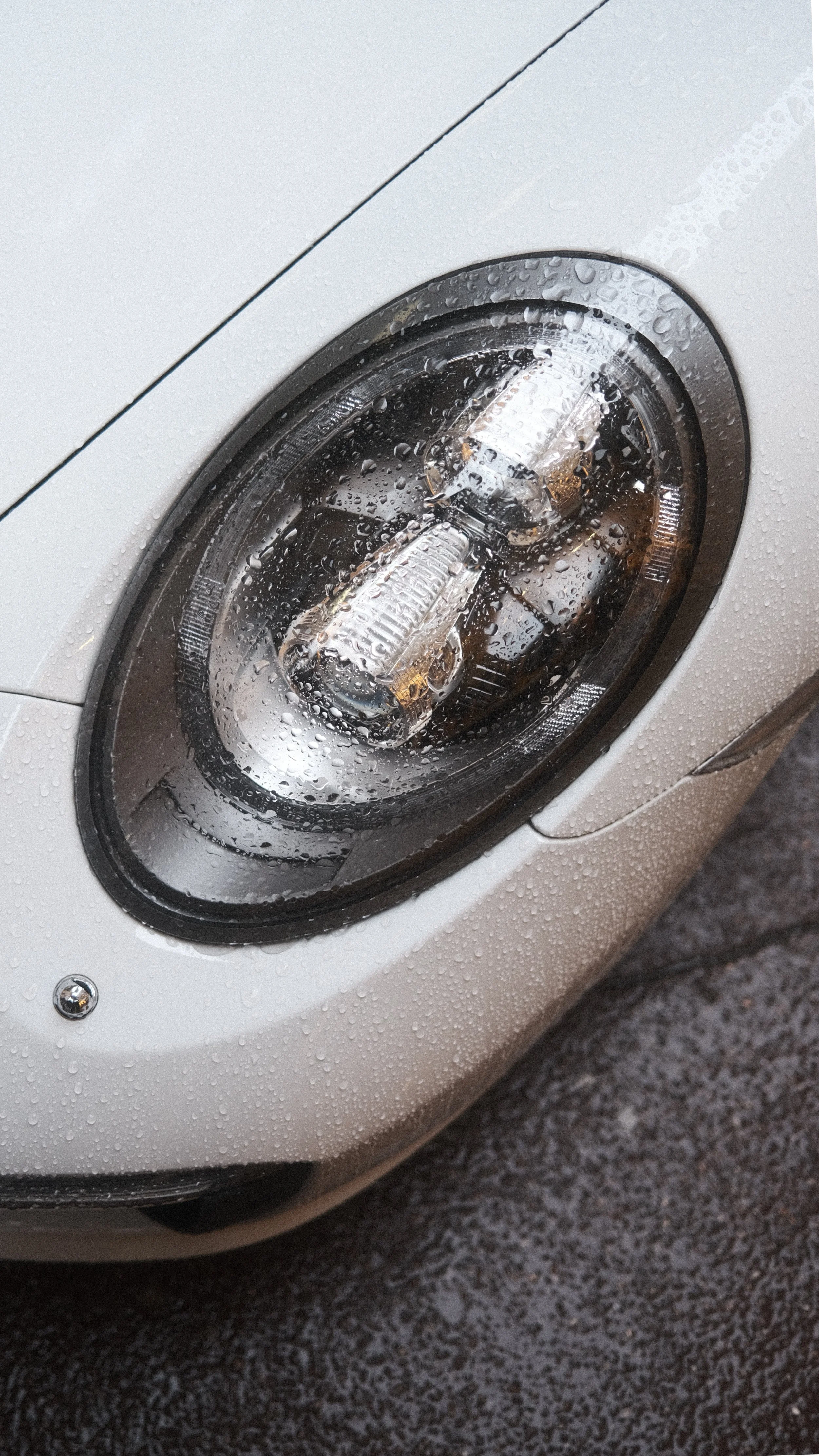 Feux de voiture sous la pluie avec des gouttelettes d'eau sur le phare