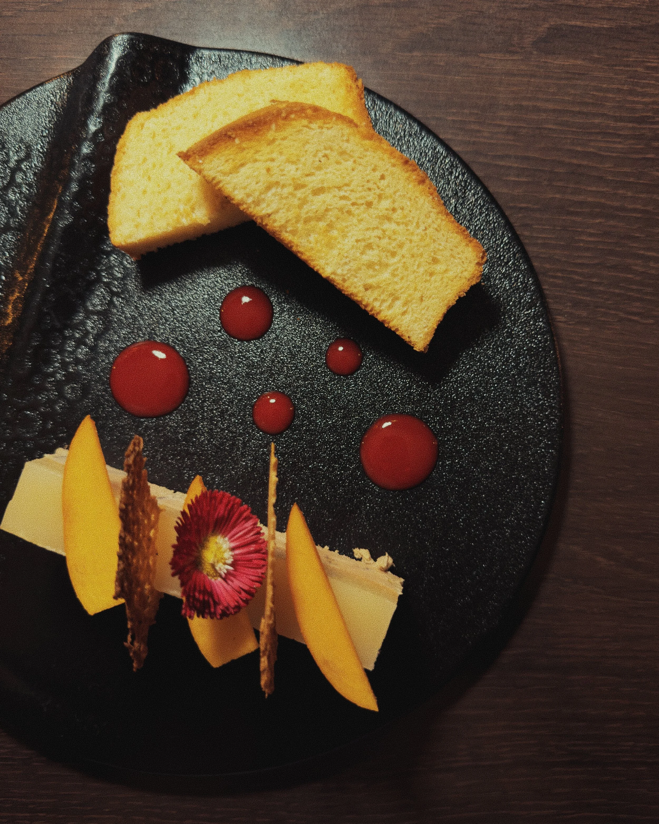 Foie gras avec décoration de fleurs en glace, nappé d'une sauce rouge, présenté sur une assiette noire