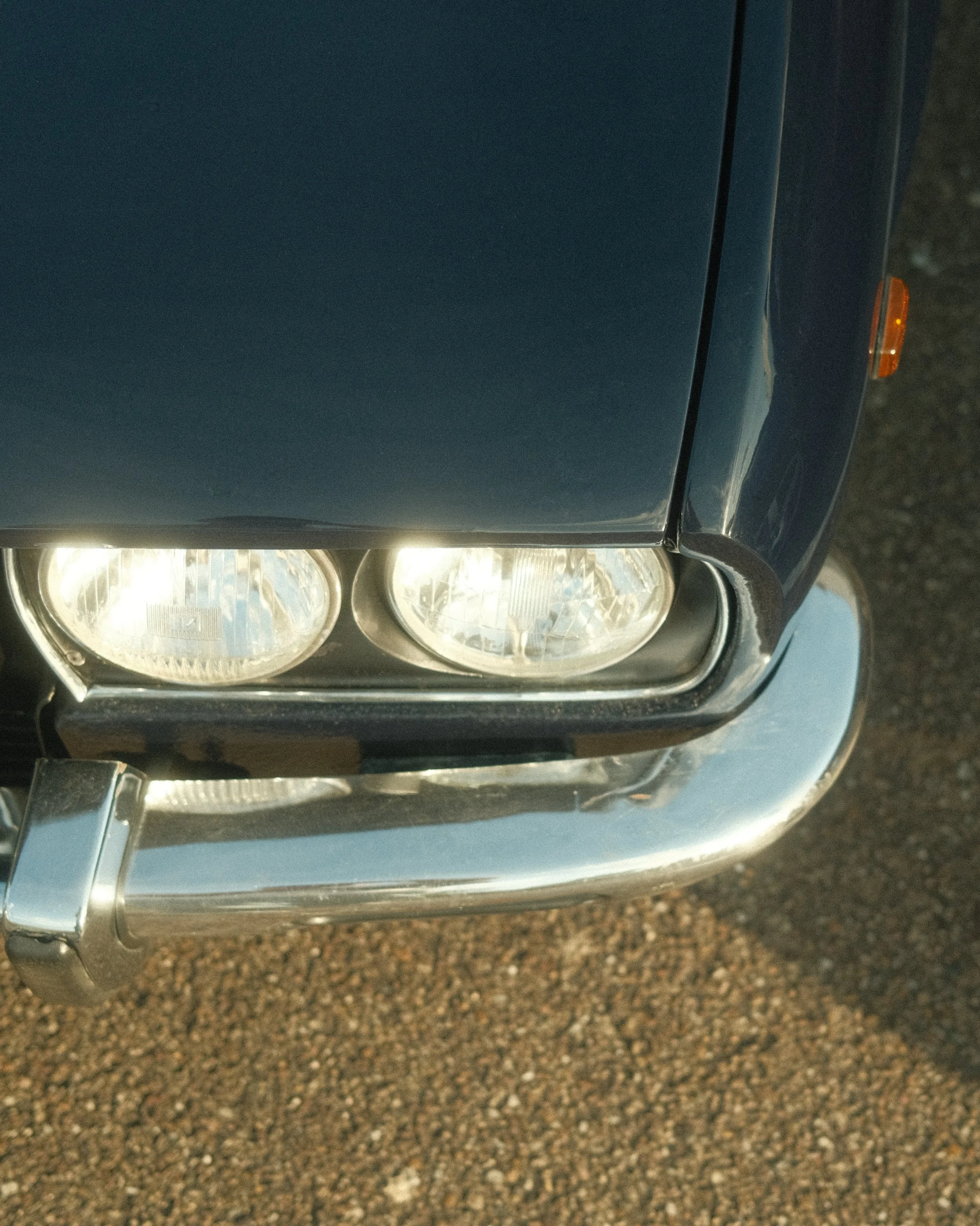 Close-up de la face avant d'une voiture, montrant les phares et la calandre, vue à partir du côté gauche.