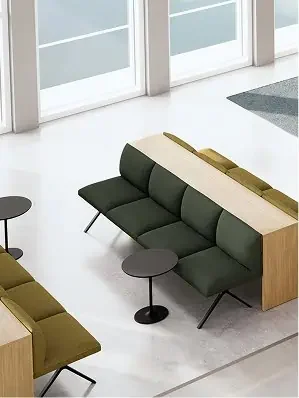 Modern seating area with a dark green sofa, a small round black table, and a mustard-colored sofa in a brightly lit room with large glass doors.