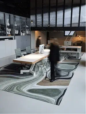 Modern office space with a white table, computers, and chairs, featuring a distinctive black, white, and gray marble-patterned rug.
