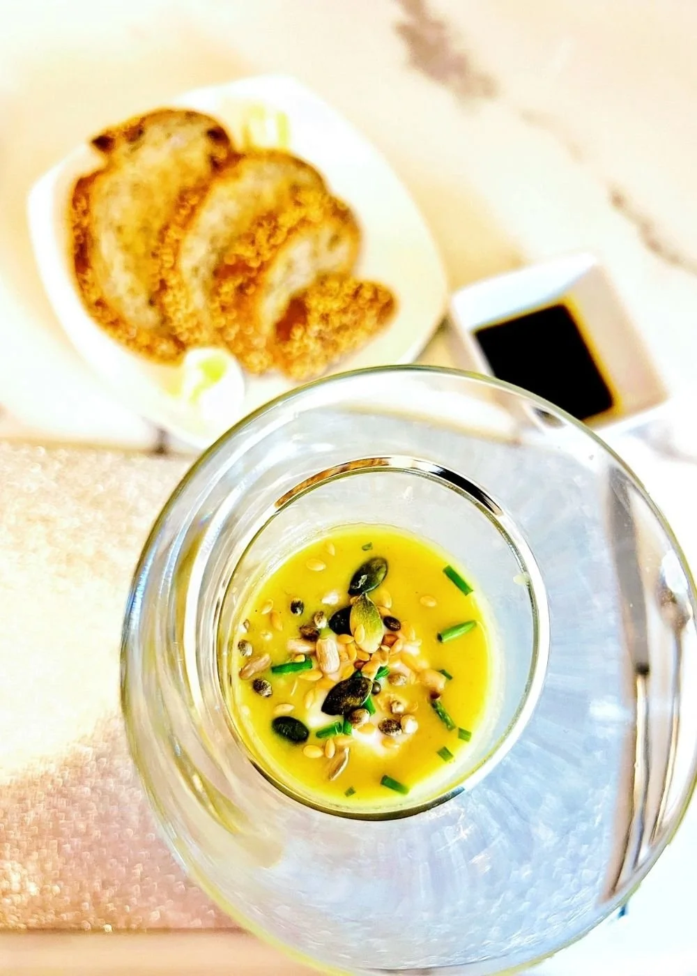FIT hot honey butternut soup in a glass bowl topped with mixed seeds and chopped chives, served alongside toasted bread