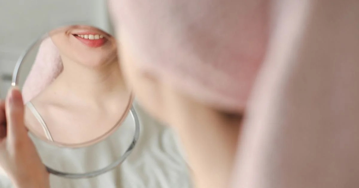 woman checking her skin and looking in a mirror