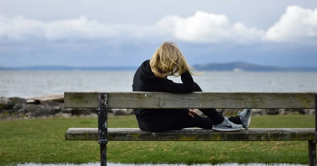 woman sitting on bench and gazing out to sea