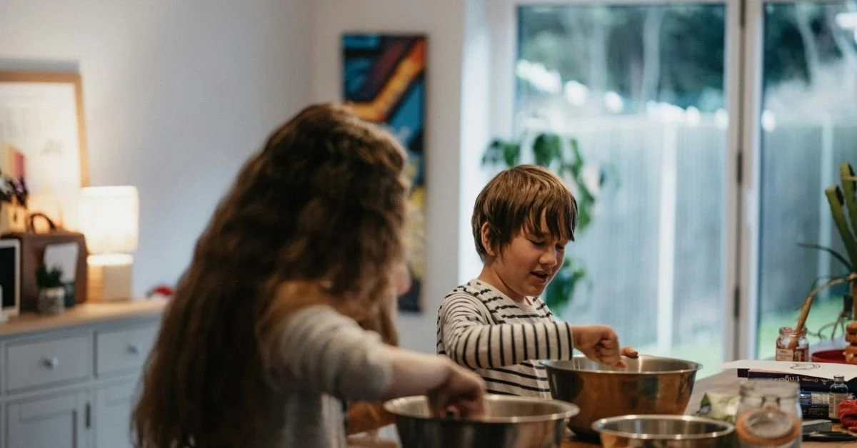 two children in a kitchen preparing food