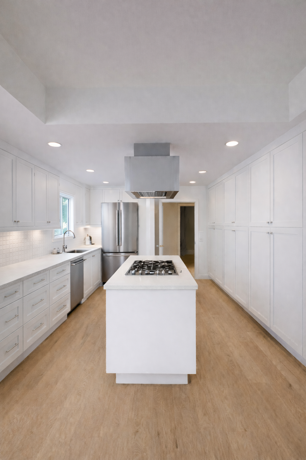Modern kitchen renovation with white cabinets, stainless steel appliances, wooden flooring, and a central island with a gas stove.