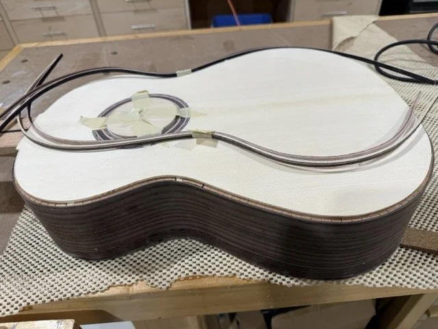 Channels are cut around the front and back of the guitar forming an area to which the binding trim pieces are to be glued to