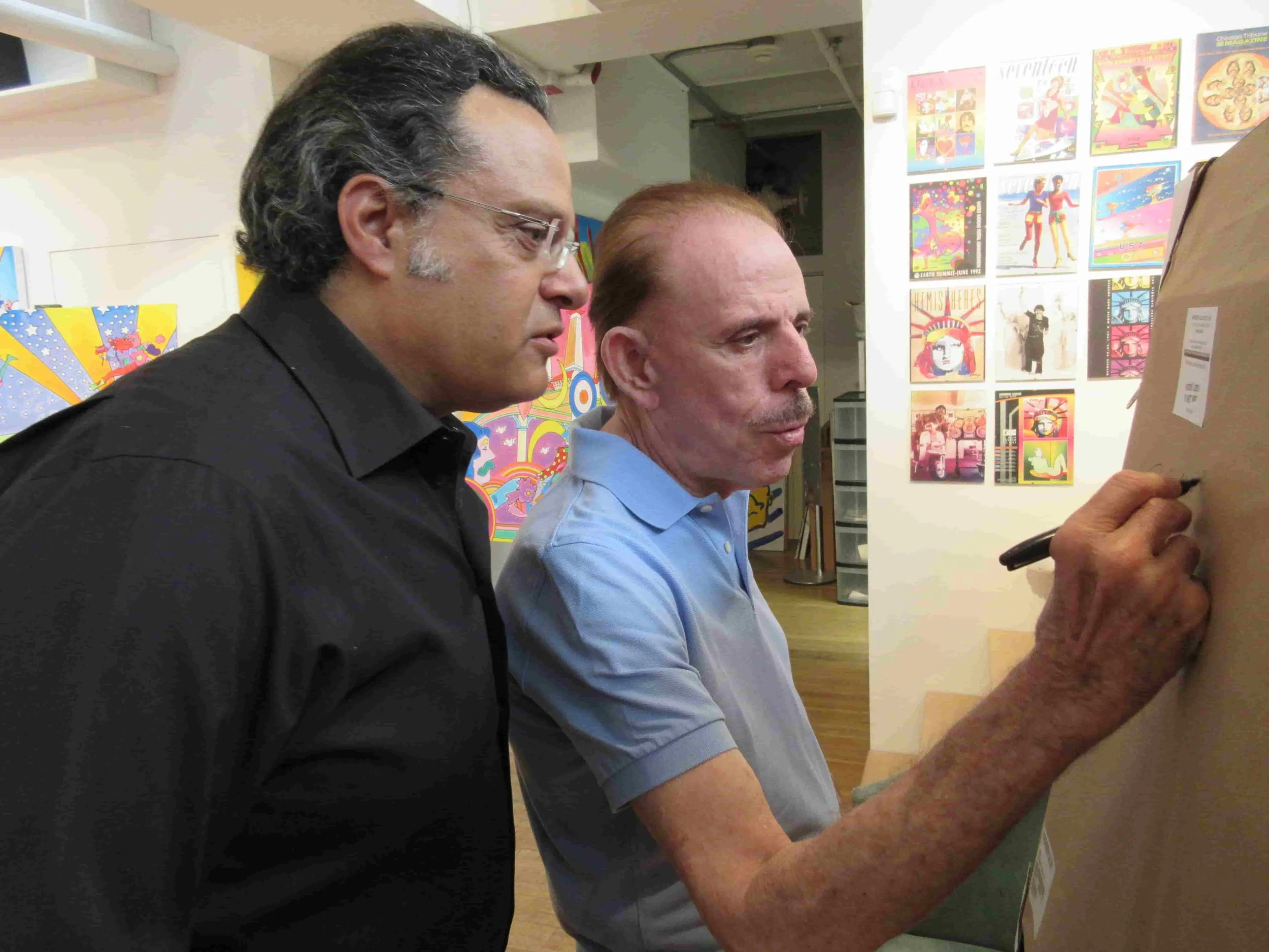The artist ZARUM with the artist Peter Max in his New York Studio. Peter Max is signing a drawing he made specifically for Zarum.